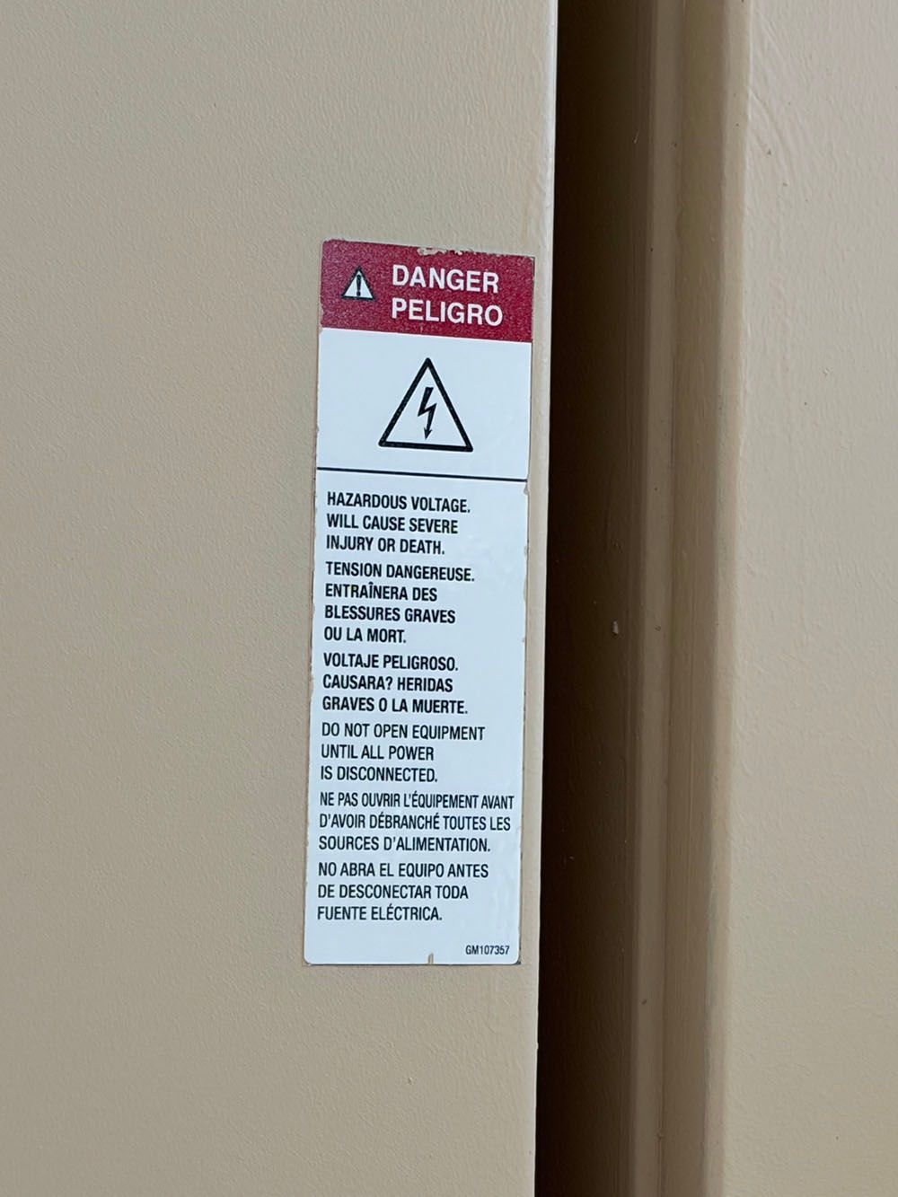 Danger/Peligro electrical warning sign on a beige wall.