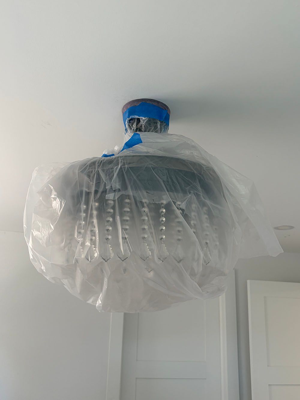 Ceiling light wrapped in plastic, with a blue cap and a white room background