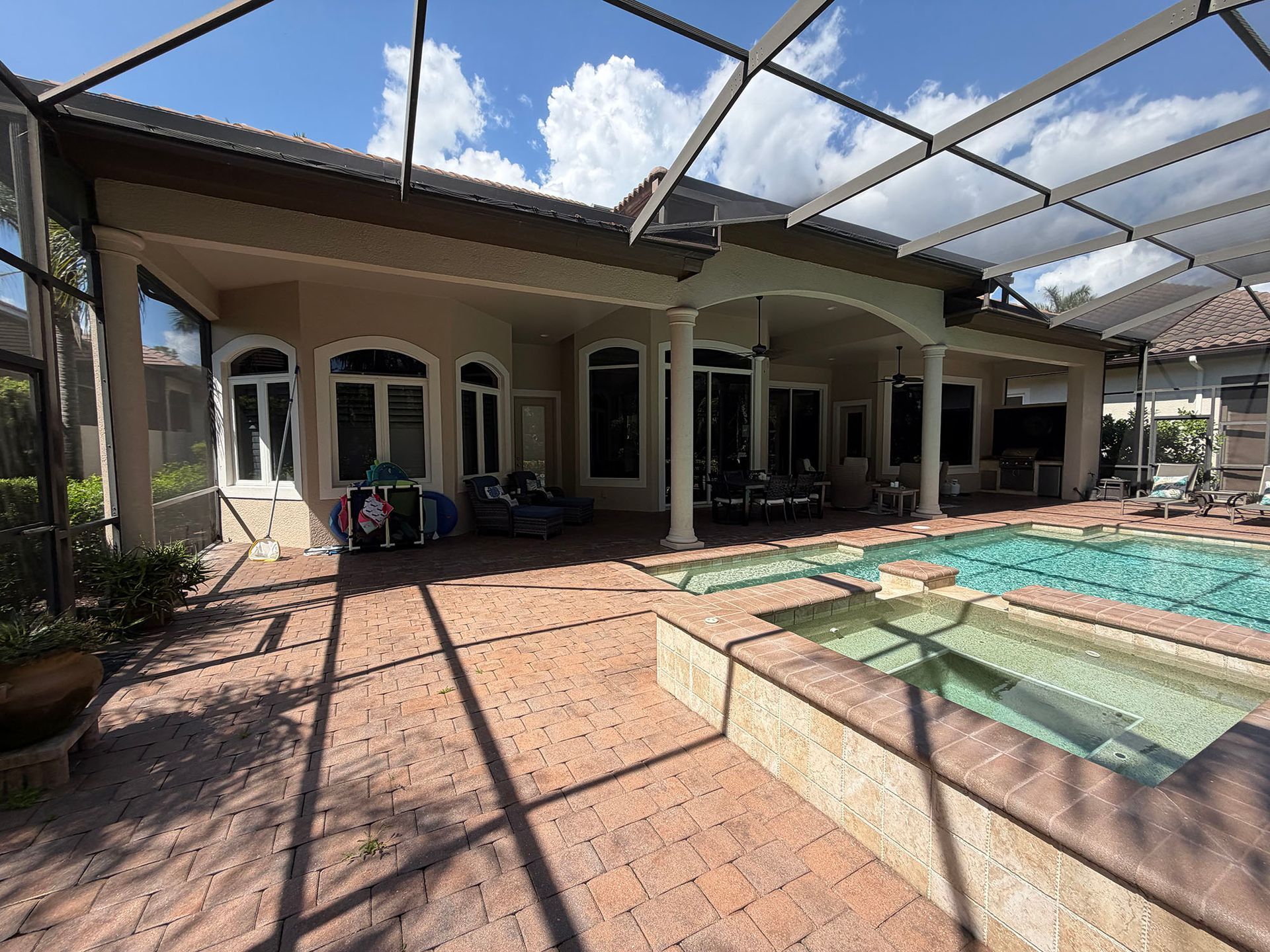 Backyard patio with a covered seating area, swimming pool, and hot tub under a clear sky