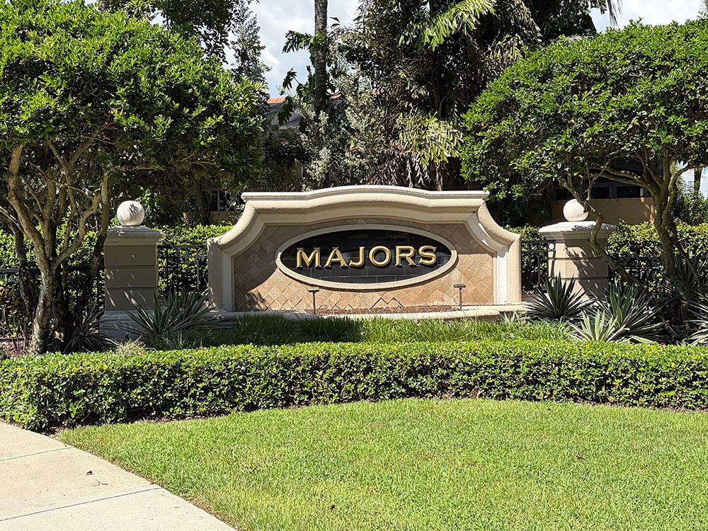 Majors entrance sign in a landscaped garden with palm trees and trimmed hedges