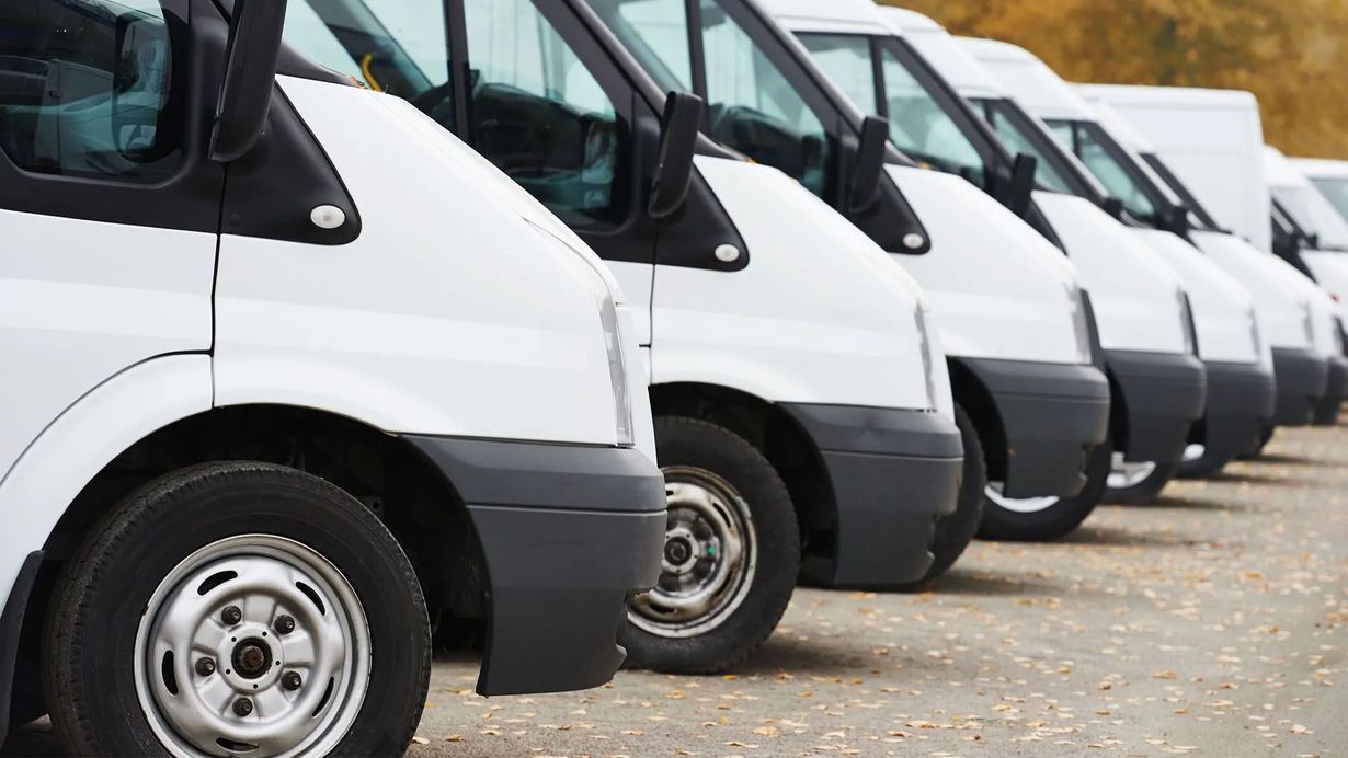 Row of white delivery vans parked diagonally along a street