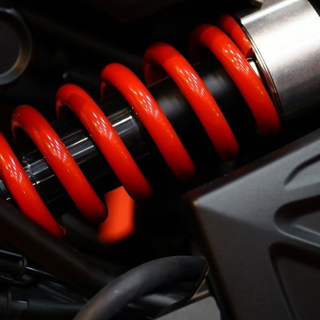 Red coil spring on a black shock absorber in a vehicle suspension assembly
