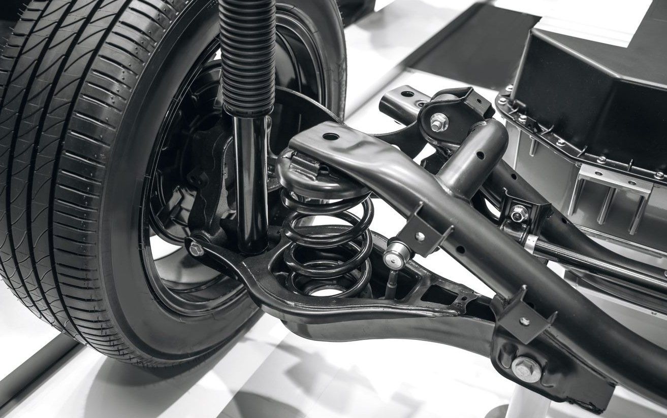 Close-up of a car rear suspension and wheel assembly with coil spring and control arms