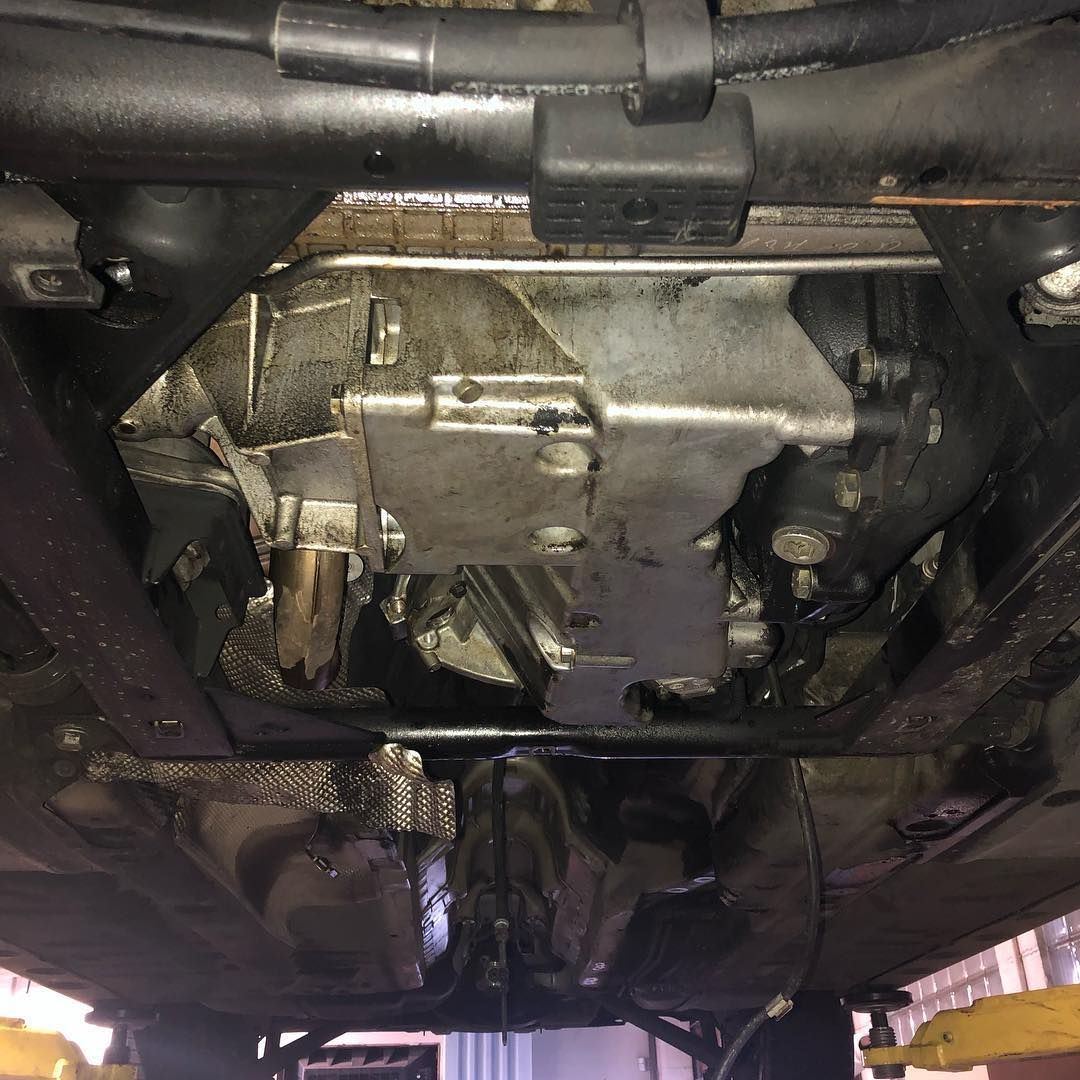 Undercarriage view of a vehicle, showing a metallic transmission housing and surrounding exhaust and suspension parts.