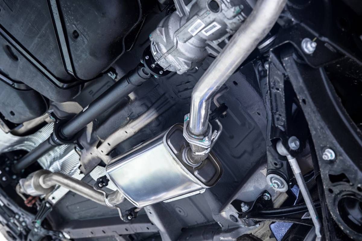 Undercarriage view of a car’s exhaust system with shiny metal muffler and piping