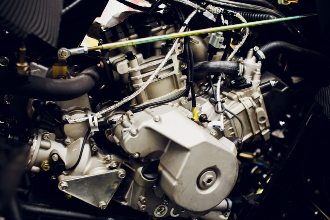 Close-up of a motorcycle engine with silver metal parts and black hoses
