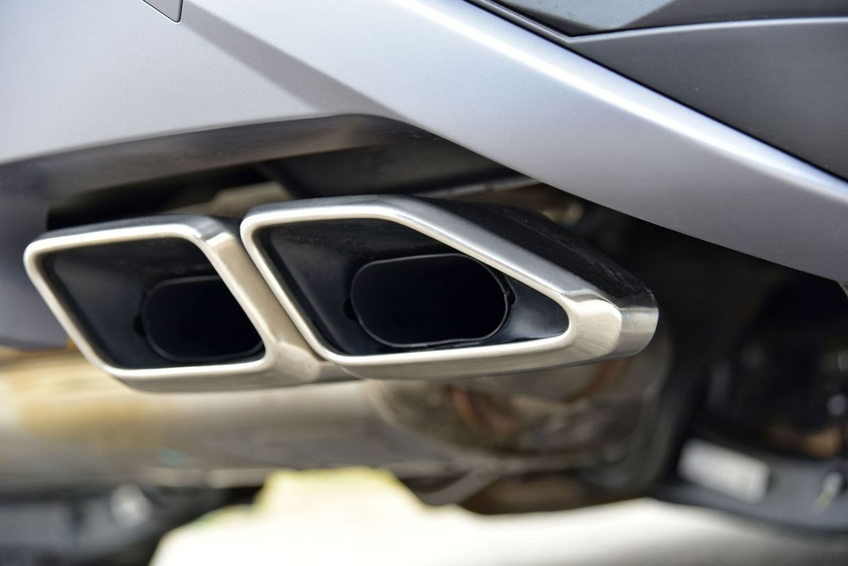 Close-up of dual chrome car exhaust tips beneath a silver bumper