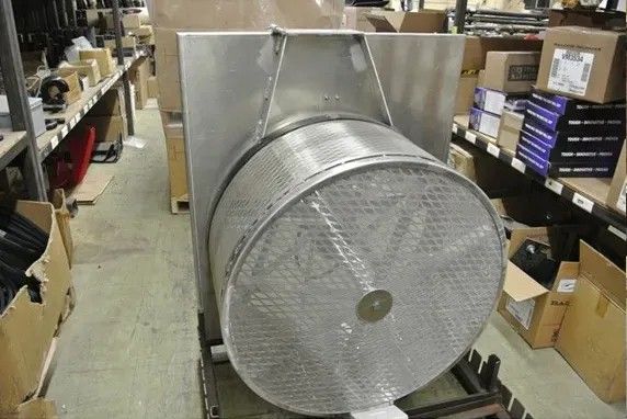 Large cylindrical metal filter, with a rectangular metal housing, in a warehouse setting.