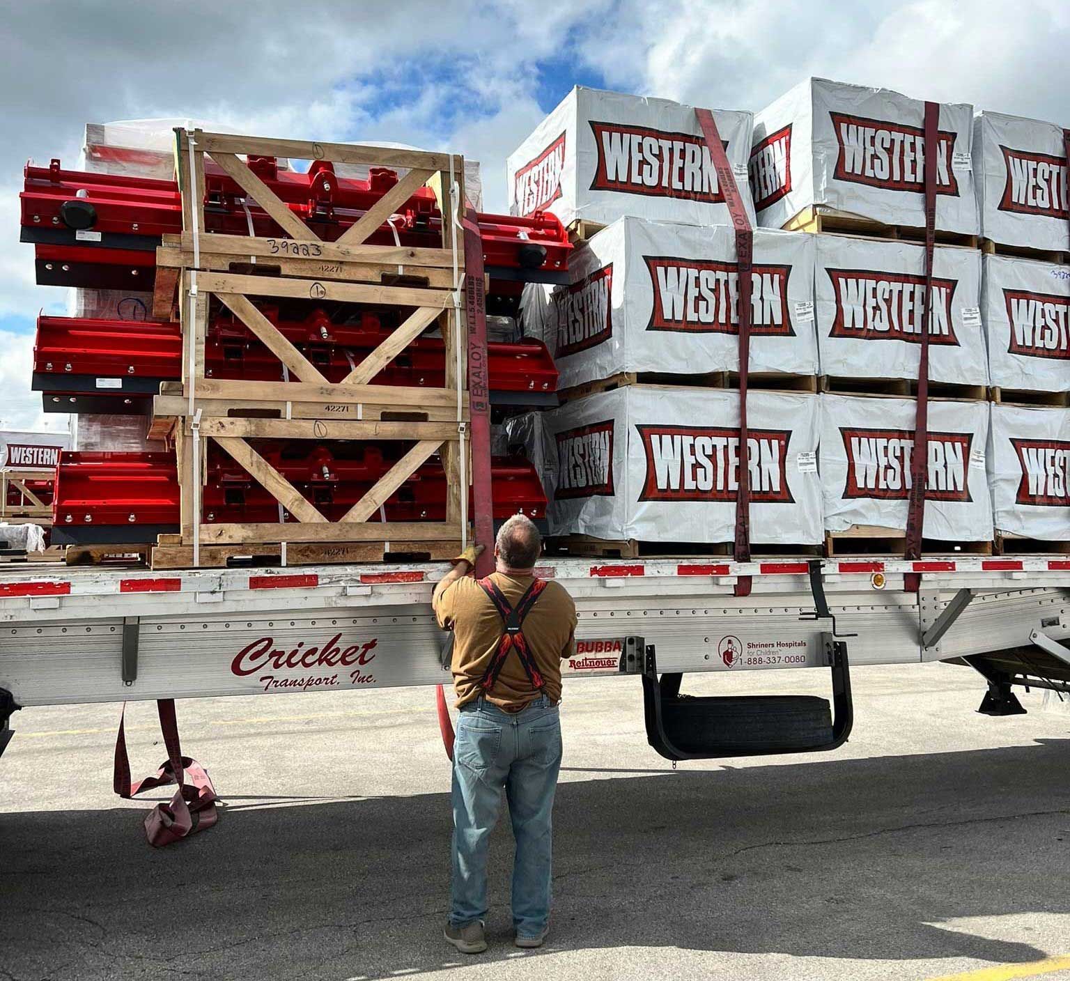 A person secures a load of pallets and crates labeled 