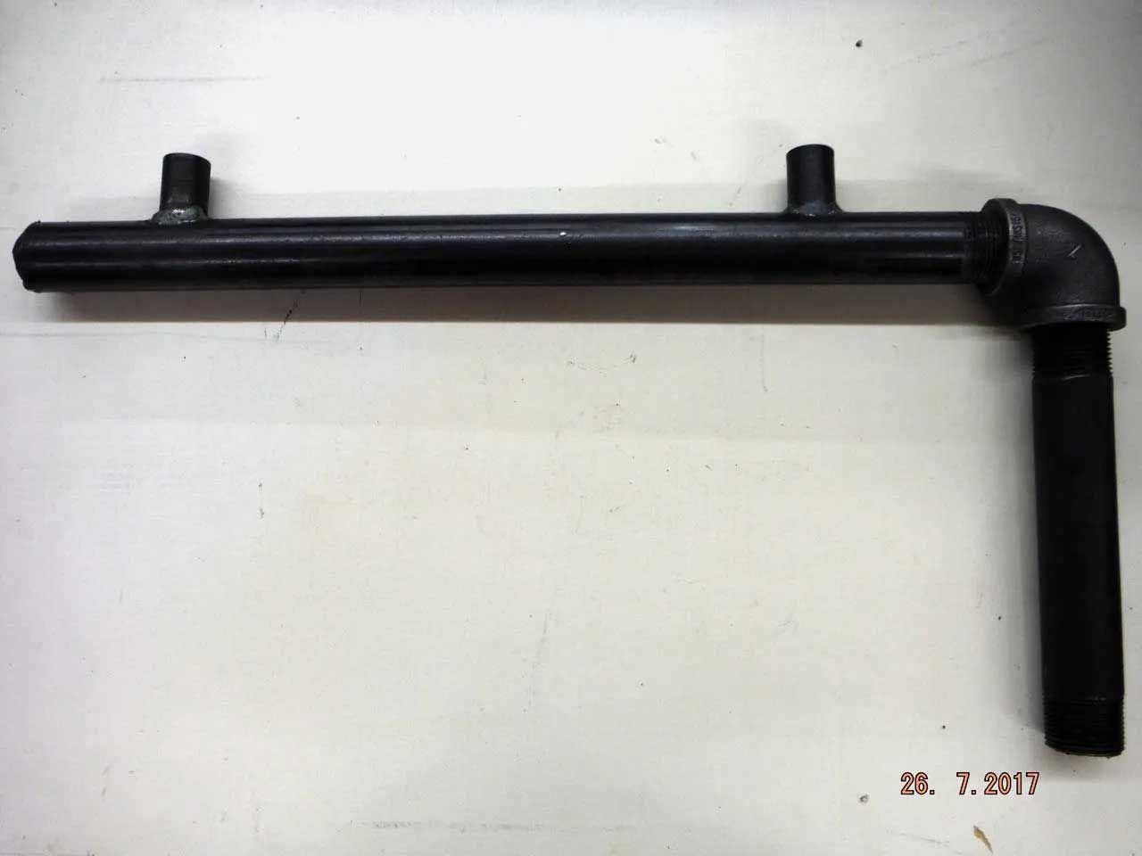 Black metal pipe assembly with two vertical tubes and a right-angle elbow. It rests on a white surface.
