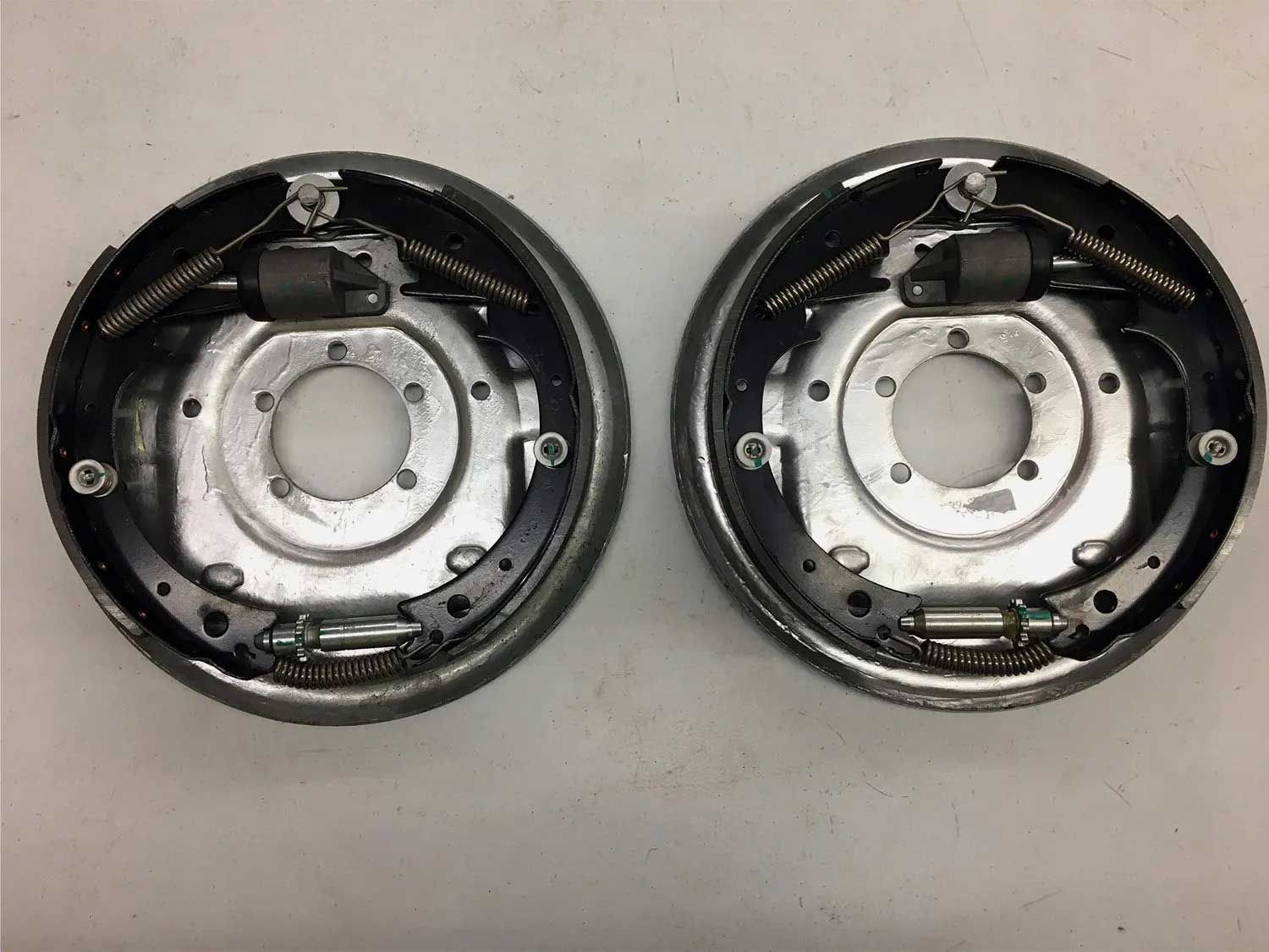 Two drum brake backing plates side by side, each with brake shoes, springs, and wheel cylinder components.