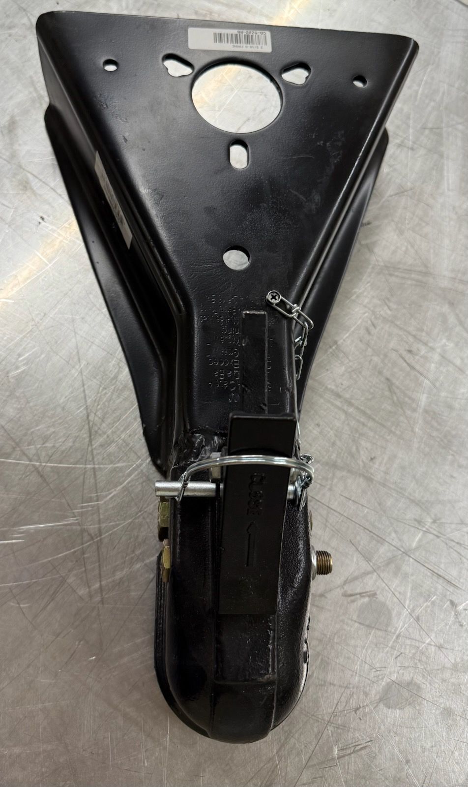 Black trailer coupler, triangular mounting bracket, attached to a metallic surface.
