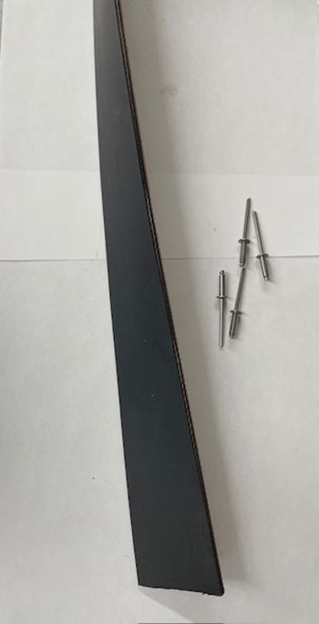 Black car trim piece with silver rivets, on white surface.