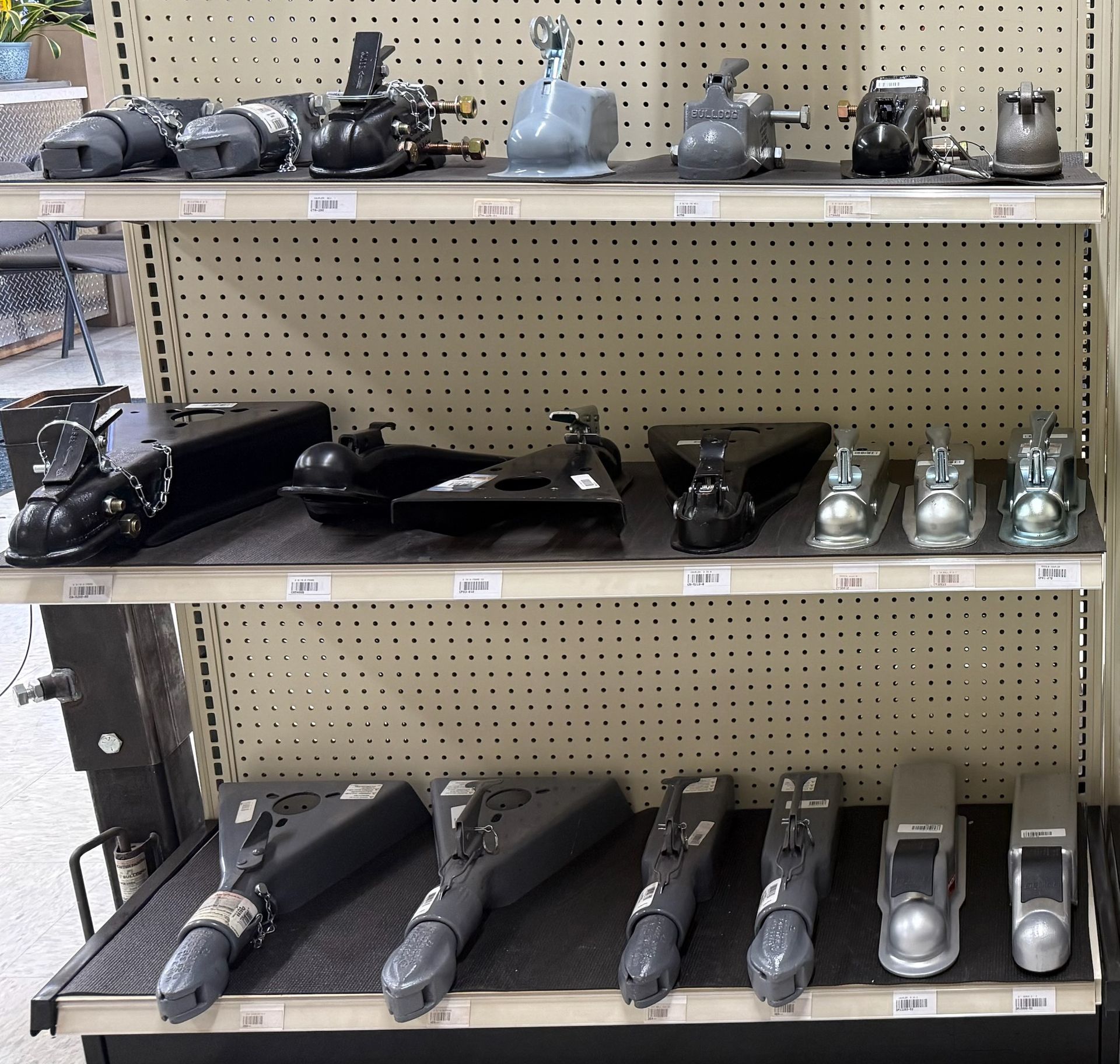 Shelves displaying various trailer hitches in a store setting.