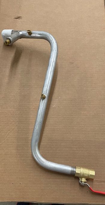 Silver metal pipe with brass fittings and a red valve, on a cardboard surface.