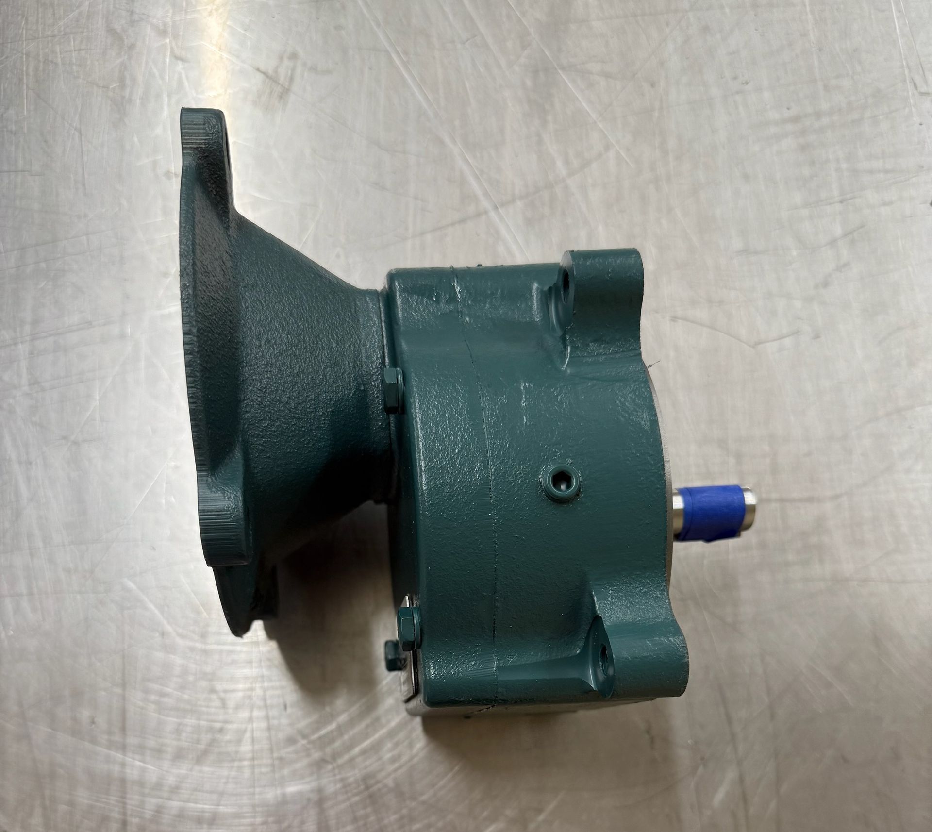 Green mechanical gear, flange at left, blue tip on right, metal surface.