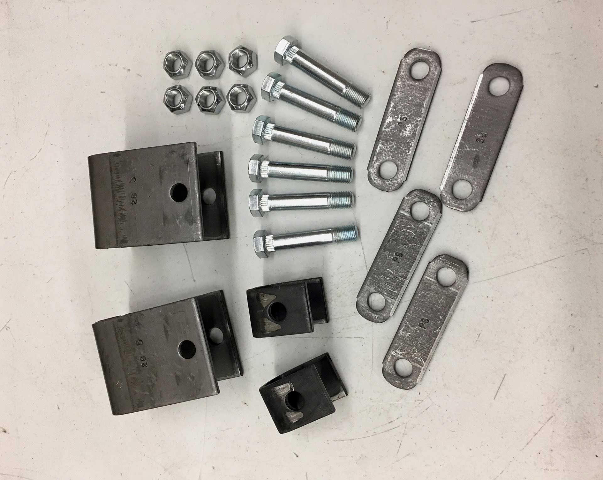A set of suspension parts: metal brackets, links, bolts, and nuts on a white surface.