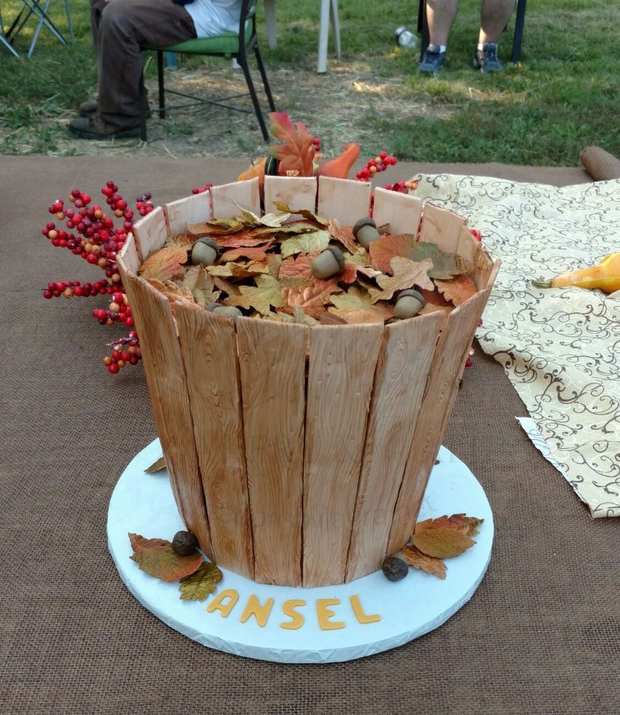 Wooden basket centerpiece filled with leaves on a white round base labeled PANSY