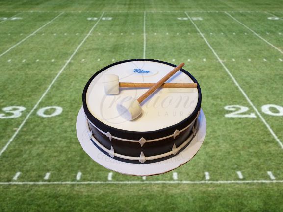Drum on a football field, with two drumsticks crossed on top