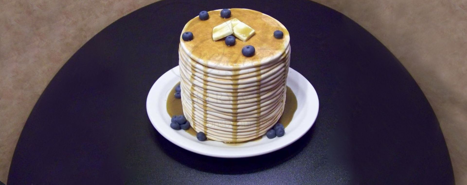 Stack of pancakes topped with butter on a white plate, cake design