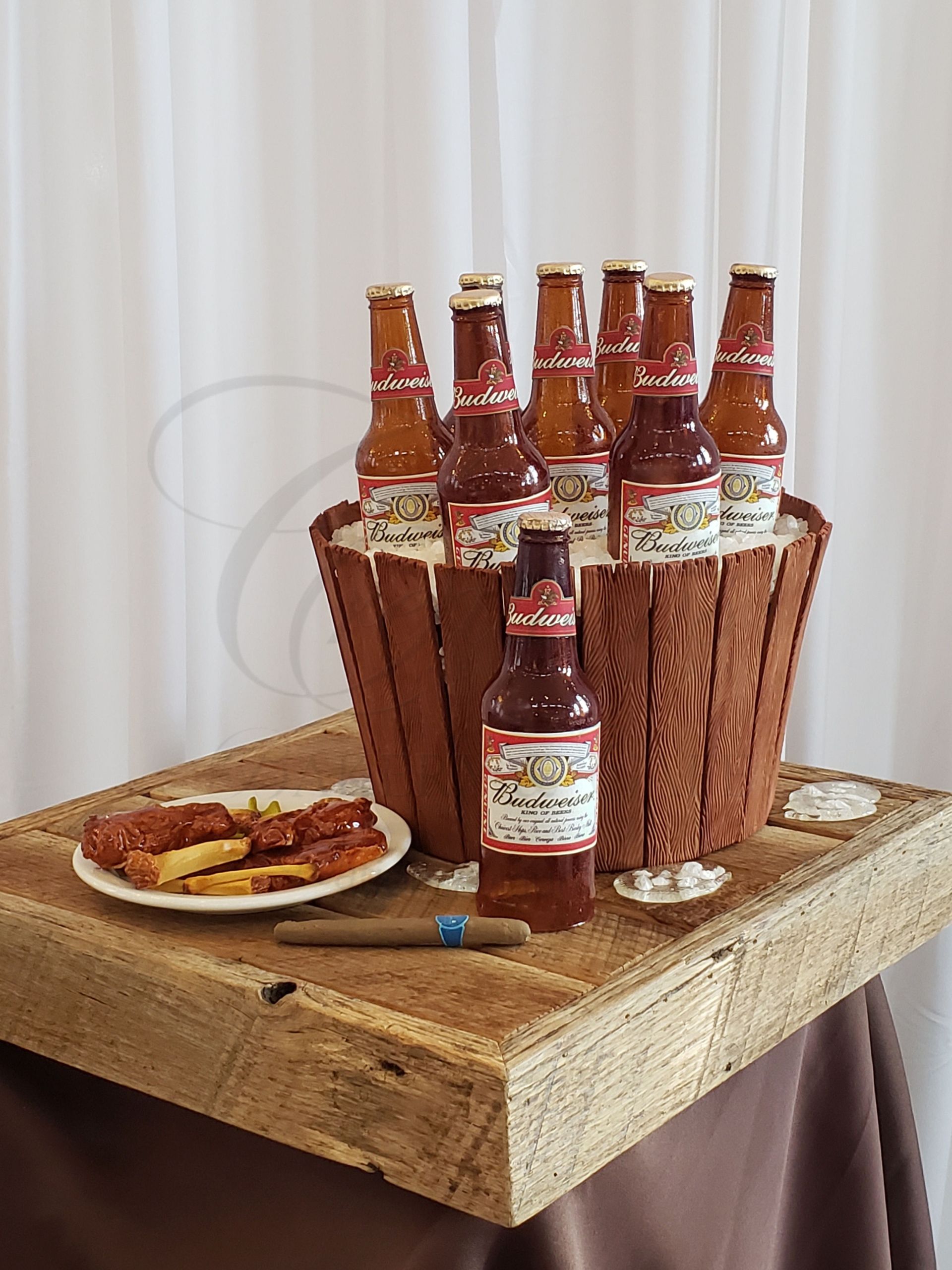 Beer bottles in a wooden caddy on a table beside a plate of food