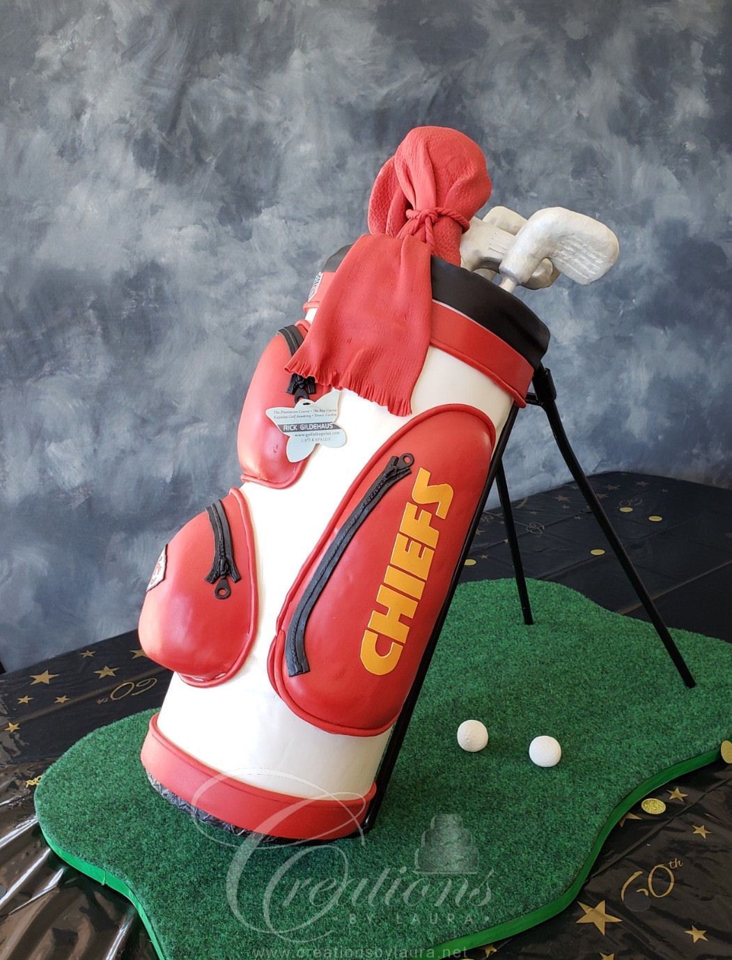 Chiefs golf bag with clubs and red cover on a green mat, with golf balls nearby
