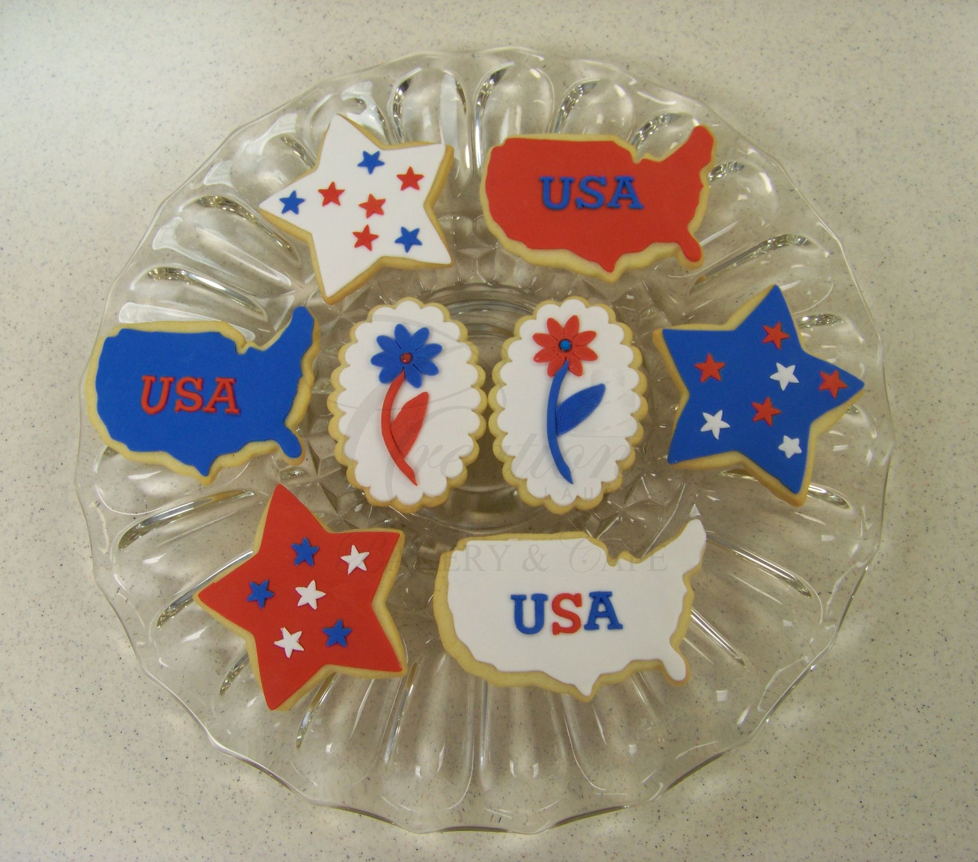 Assorted red, white, and blue USA-shaped cookies arranged on a clear plate