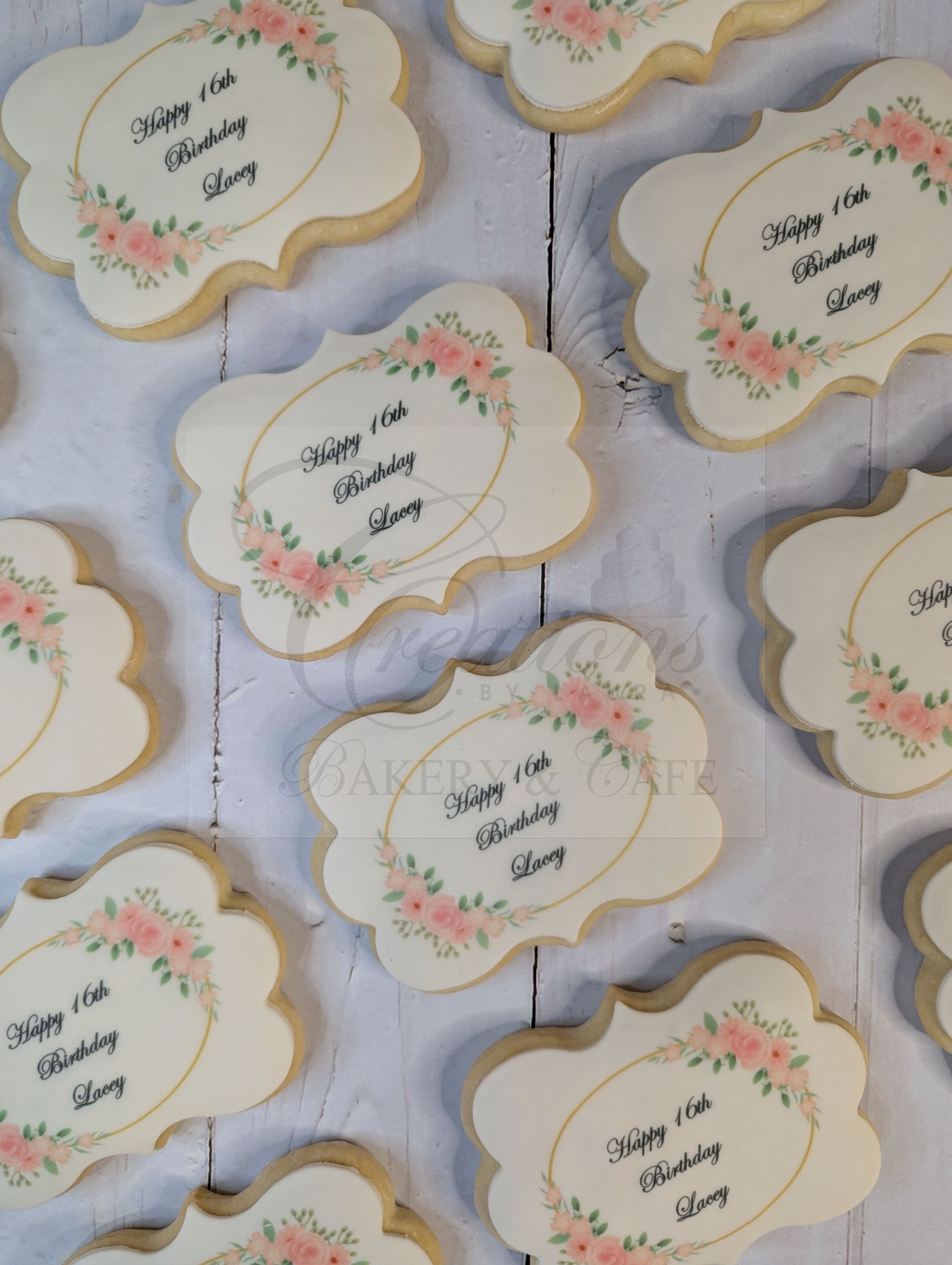 Cream cookies with floral accents and handwritten names arranged on a white surface
