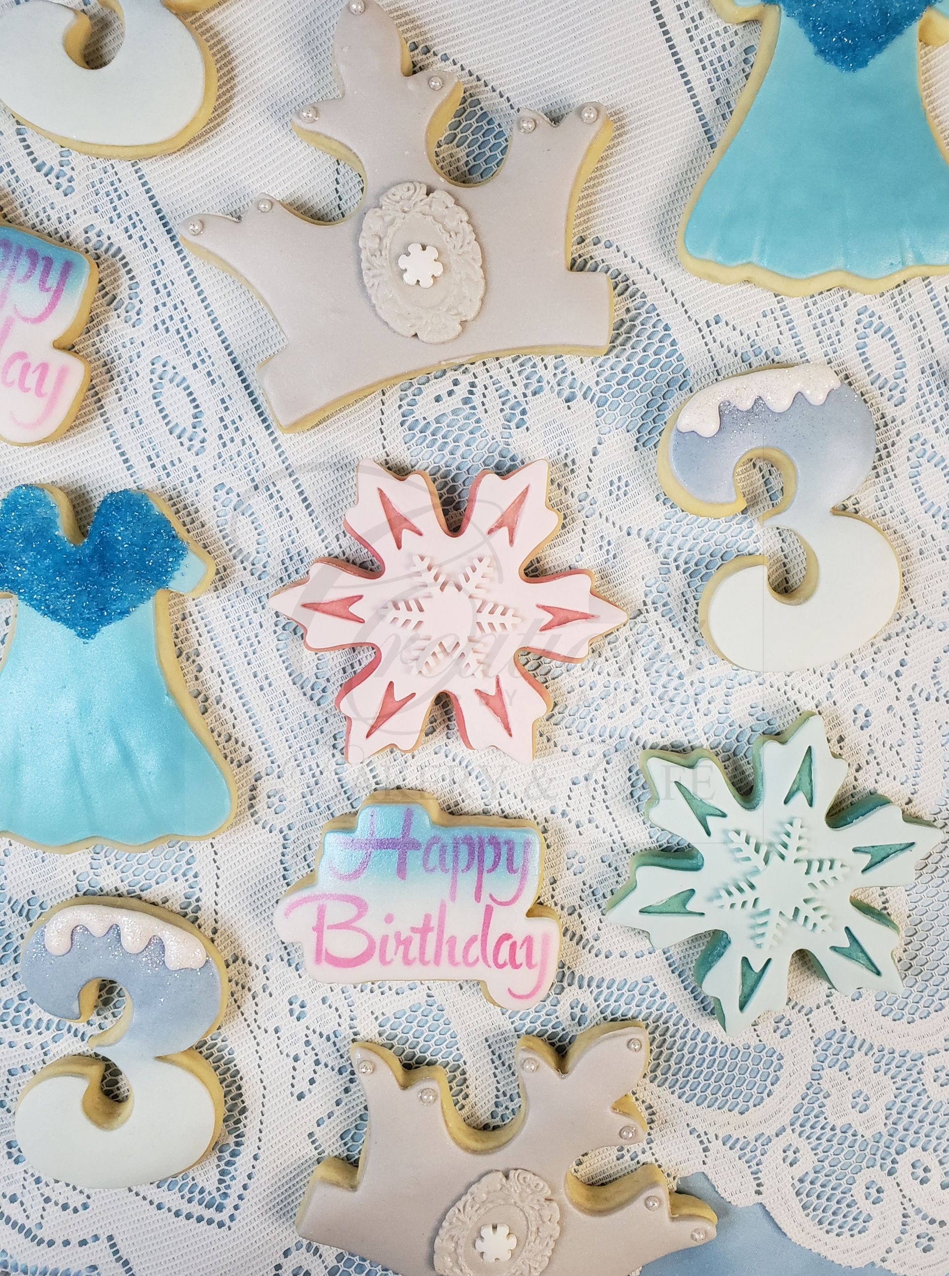 Assorted pastel birthday cookies with lace-like icing and “Happy Birthday” cookie centerpiece