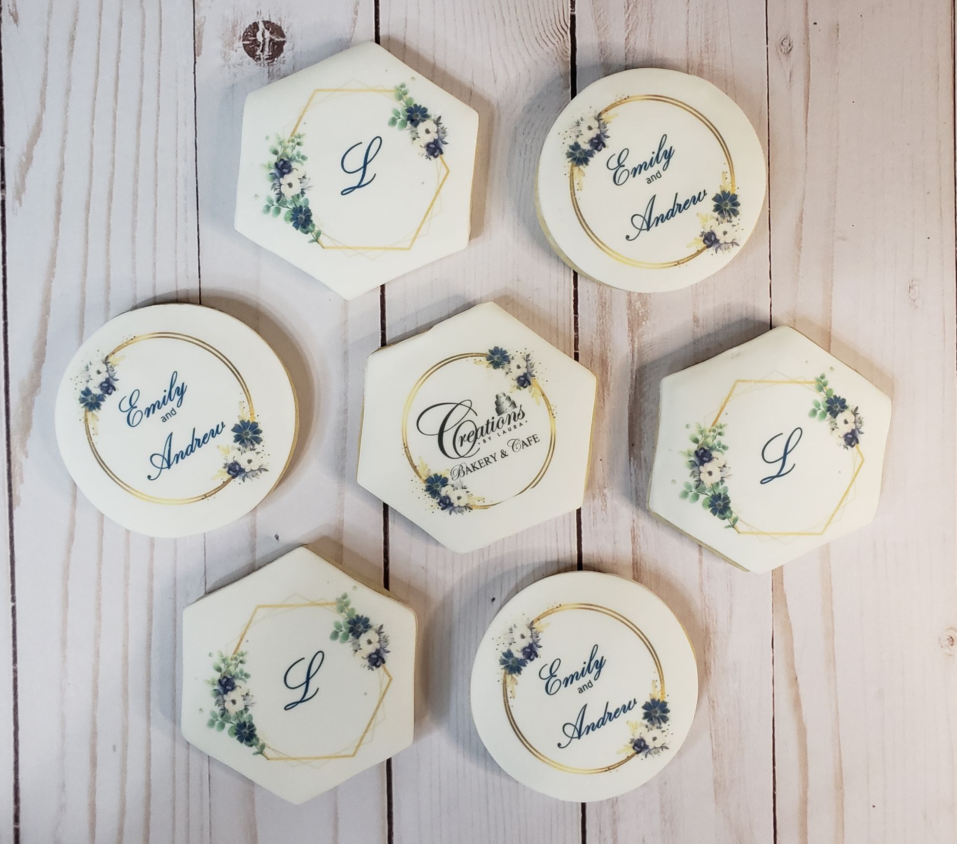 Seven hexagonal and round white floral cookies on a light wood background.