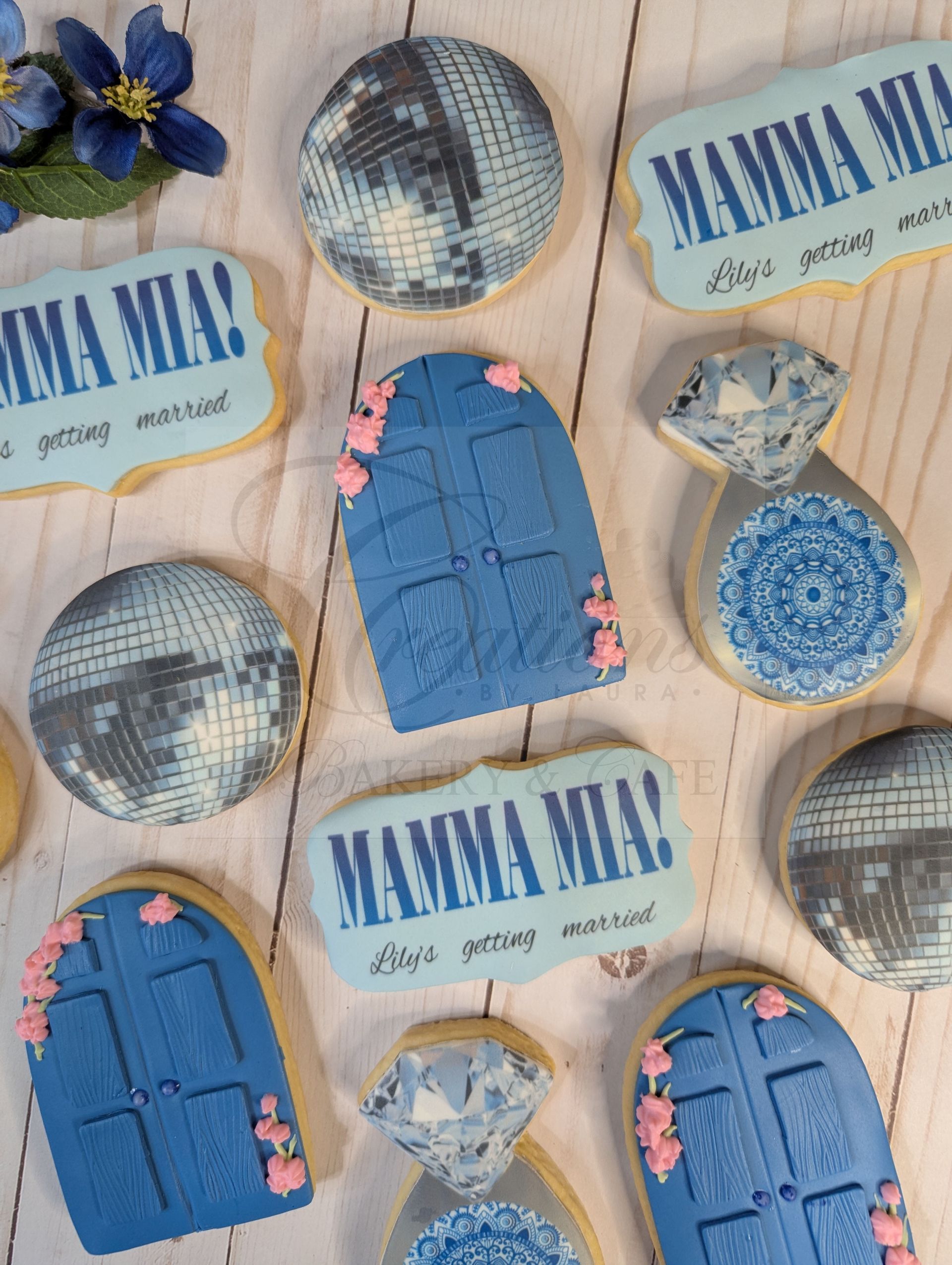 Blue and beige floral-themed cookies with “MAMA MIA” text arranged on a patterned background