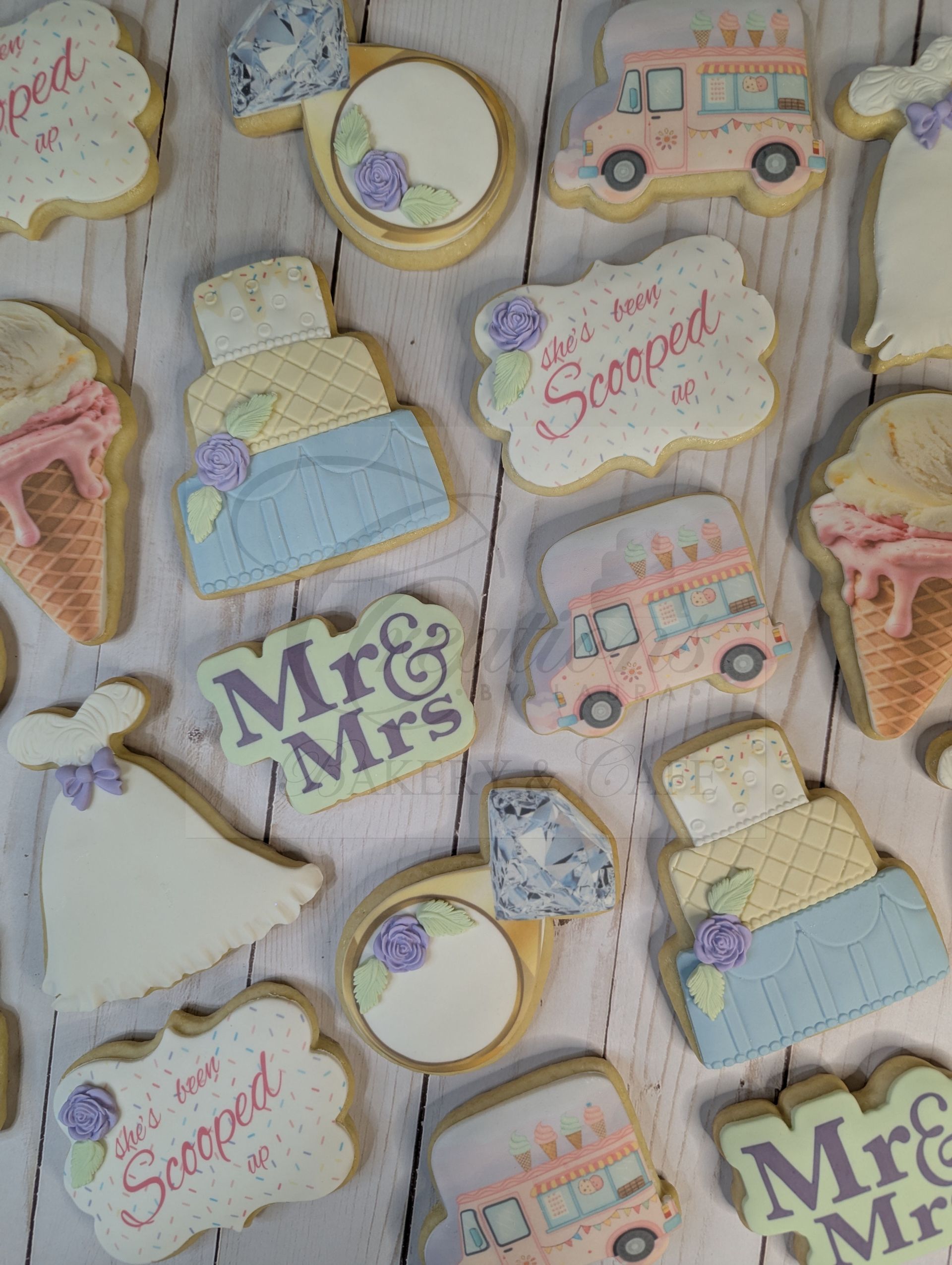 Pastel decorated cookies with “Mr & Mrs,” “Siempre,” rings, cakes, and pink buses on a white background