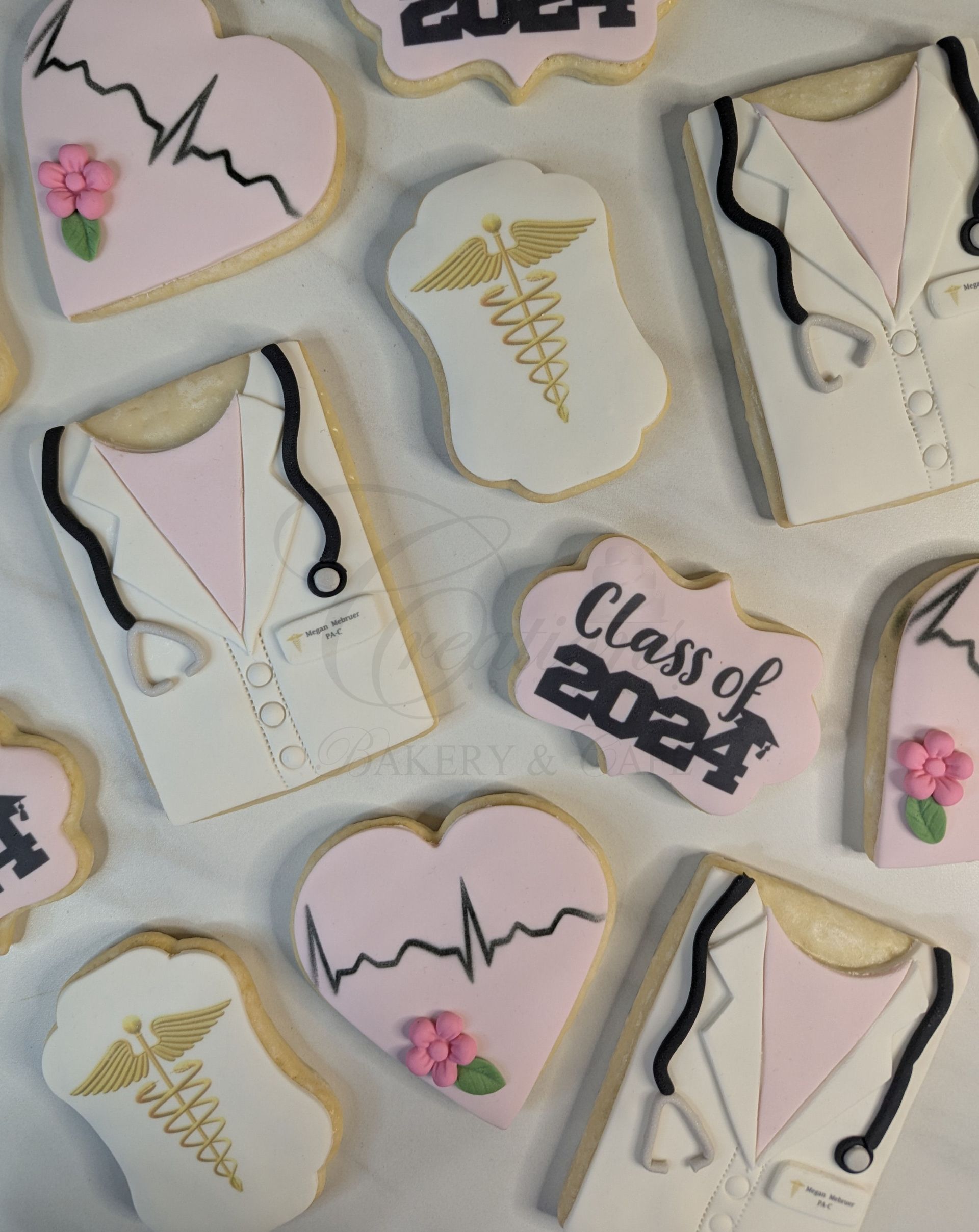 Assorted pastel cookies with pink piping, flowers, and “Class of 2024” graduation designs