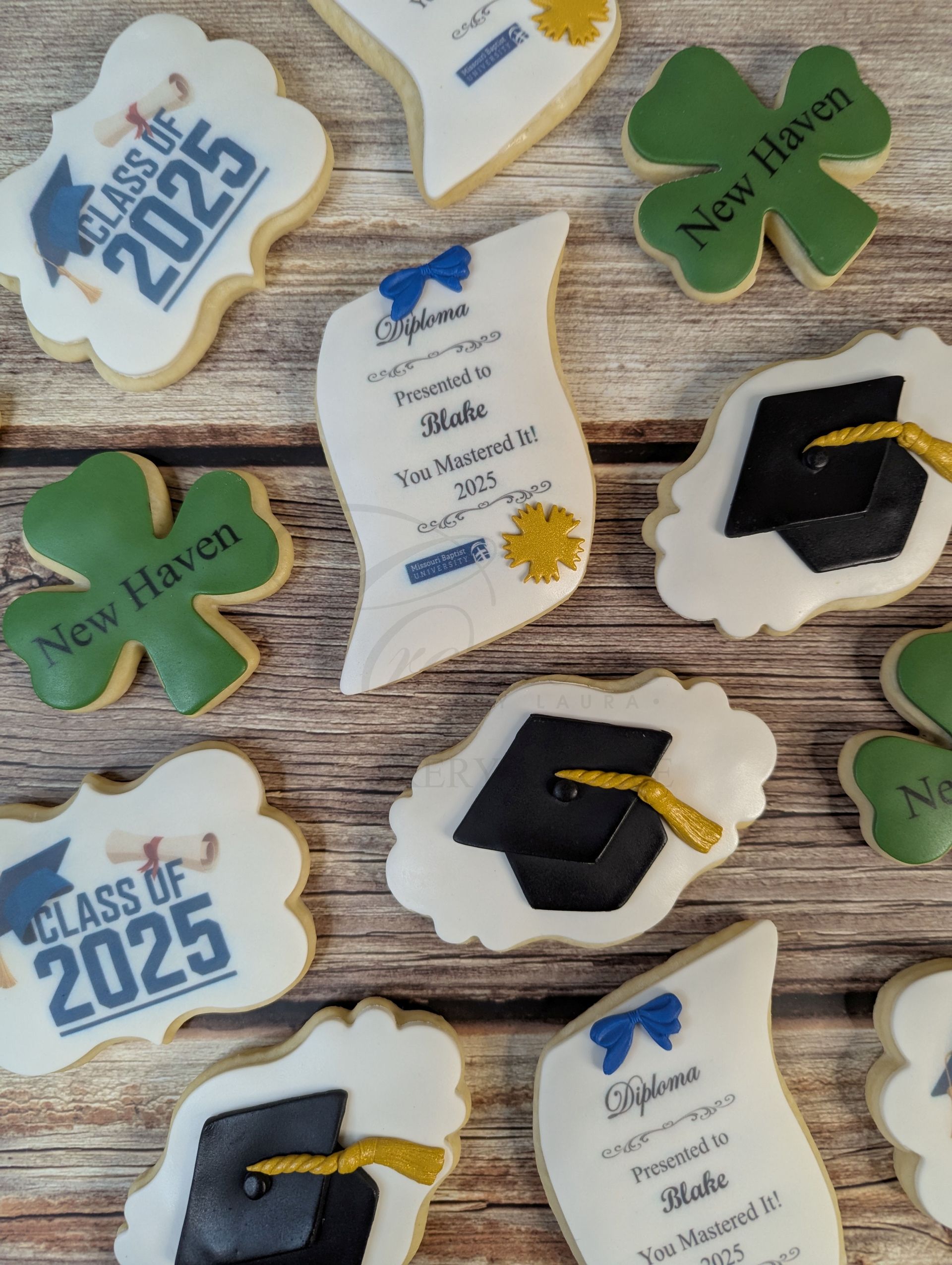Assorted graduation cookies with blue, green, and black designs on a wooden surface