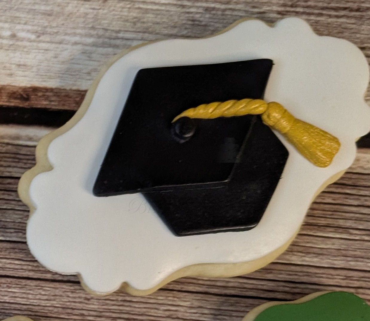 Black graduation cap with gold tassel on a white cloud-shaped plaque