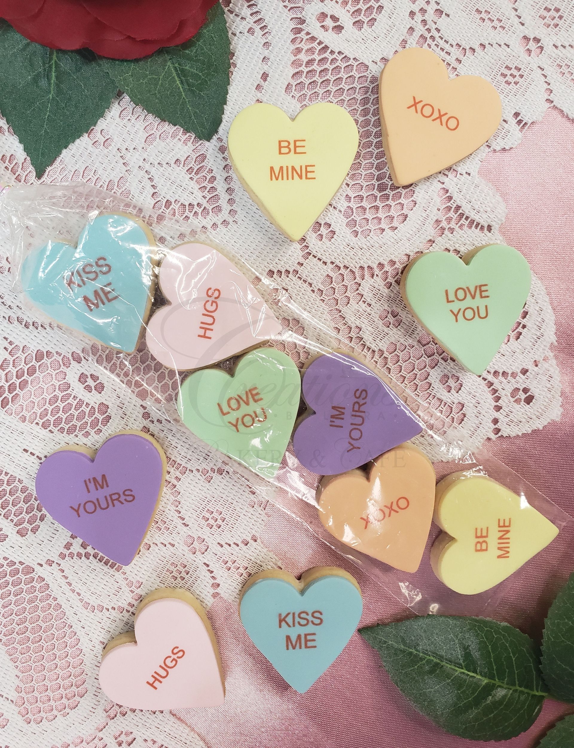 Heart-shaped paper notes with love messages in pastel colors arranged on a lace background.