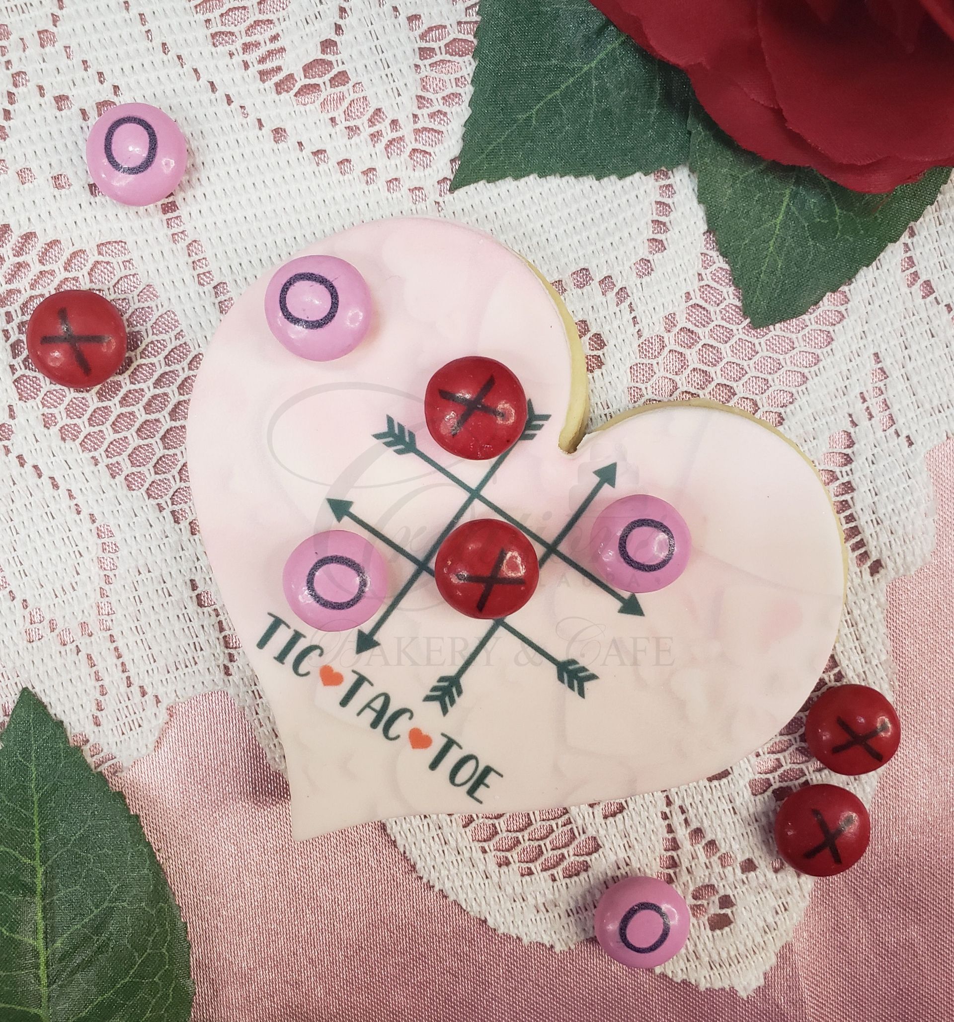 Heart-shaped tic-tac-toe craft with pink and red buttons on lace, accented by a red rose.