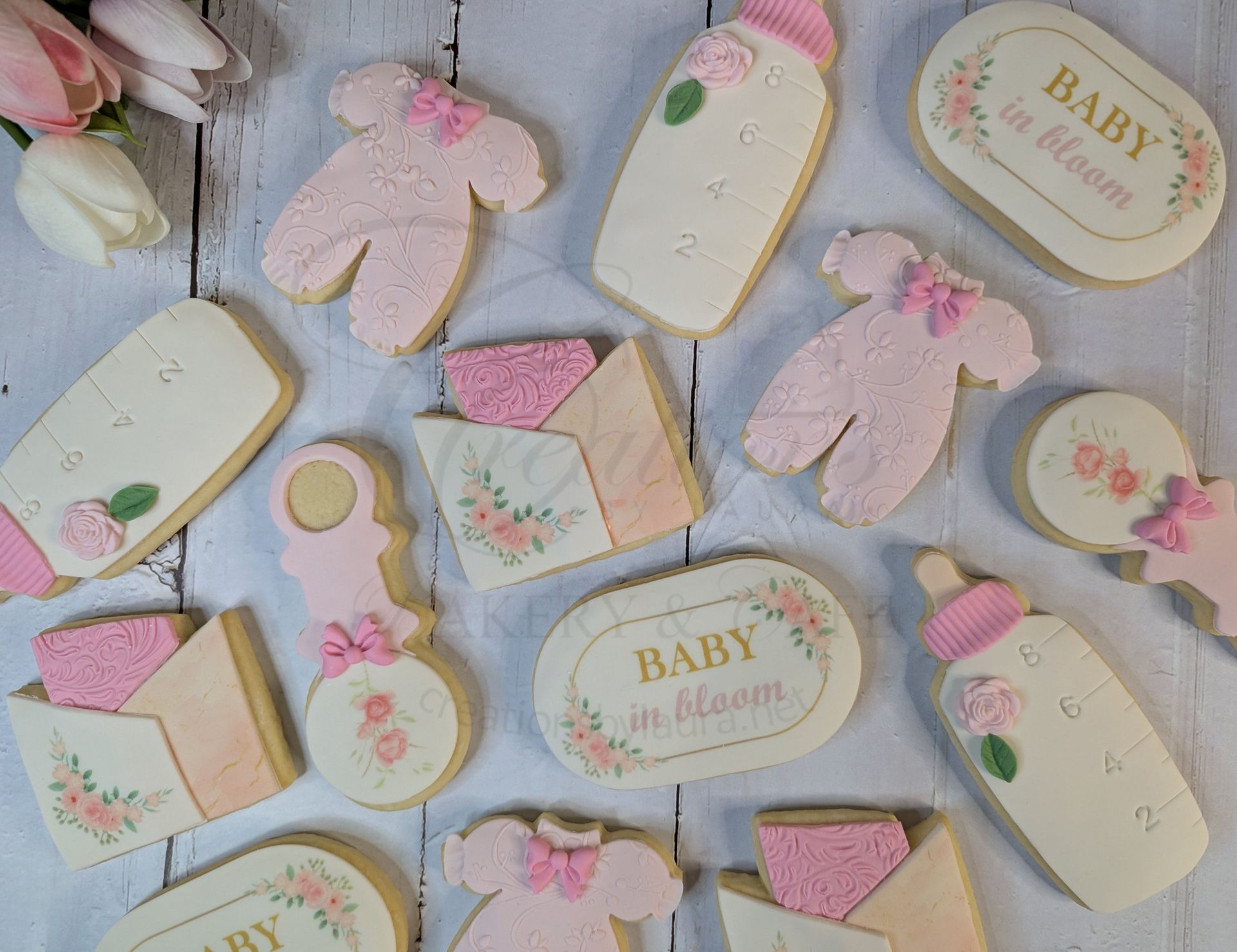Pastel baby shower cookies with pink bows and gold accents on a white surface