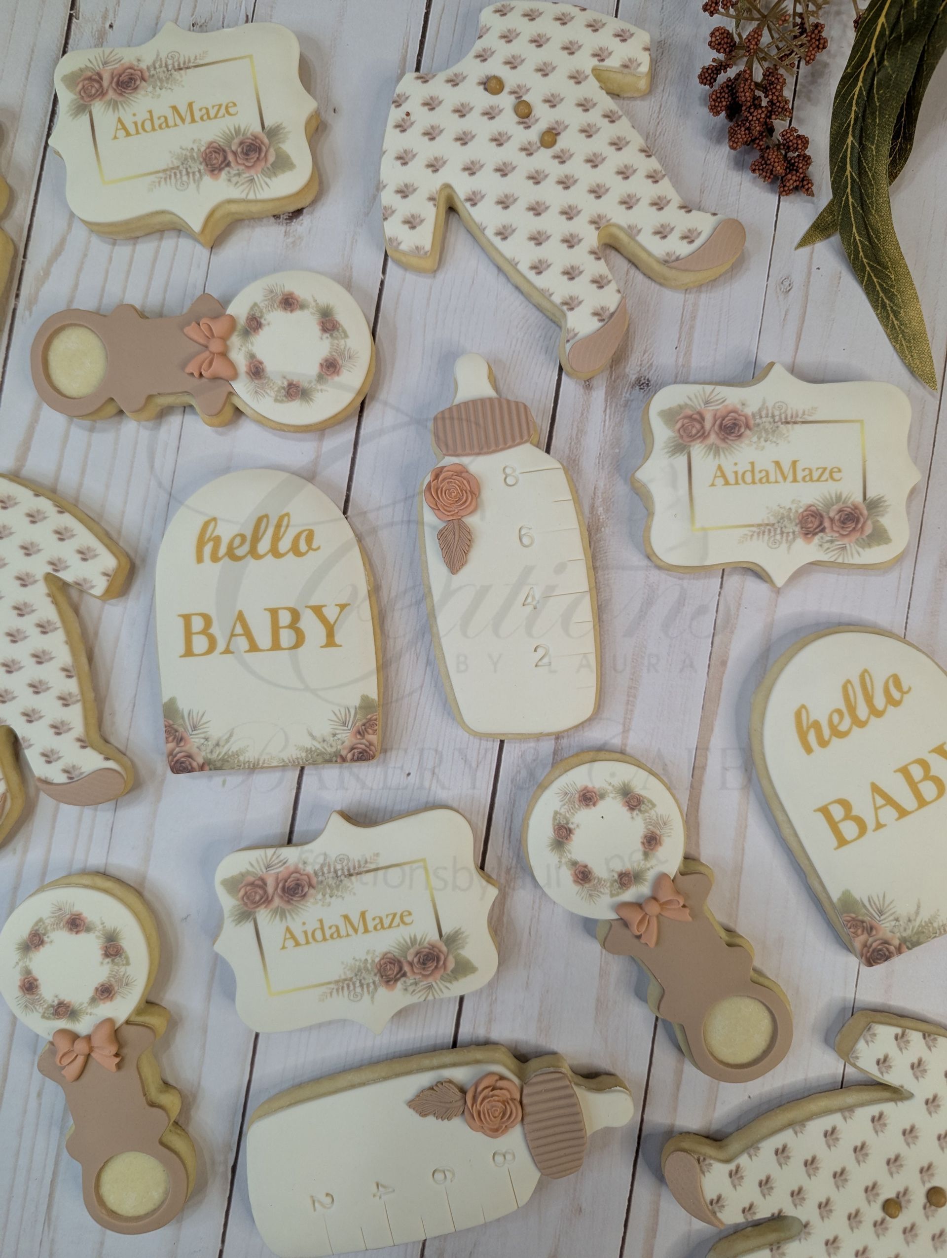 Pastel baby shower paper goods with hello BABY tags, onesies, and floral accents on a wood background