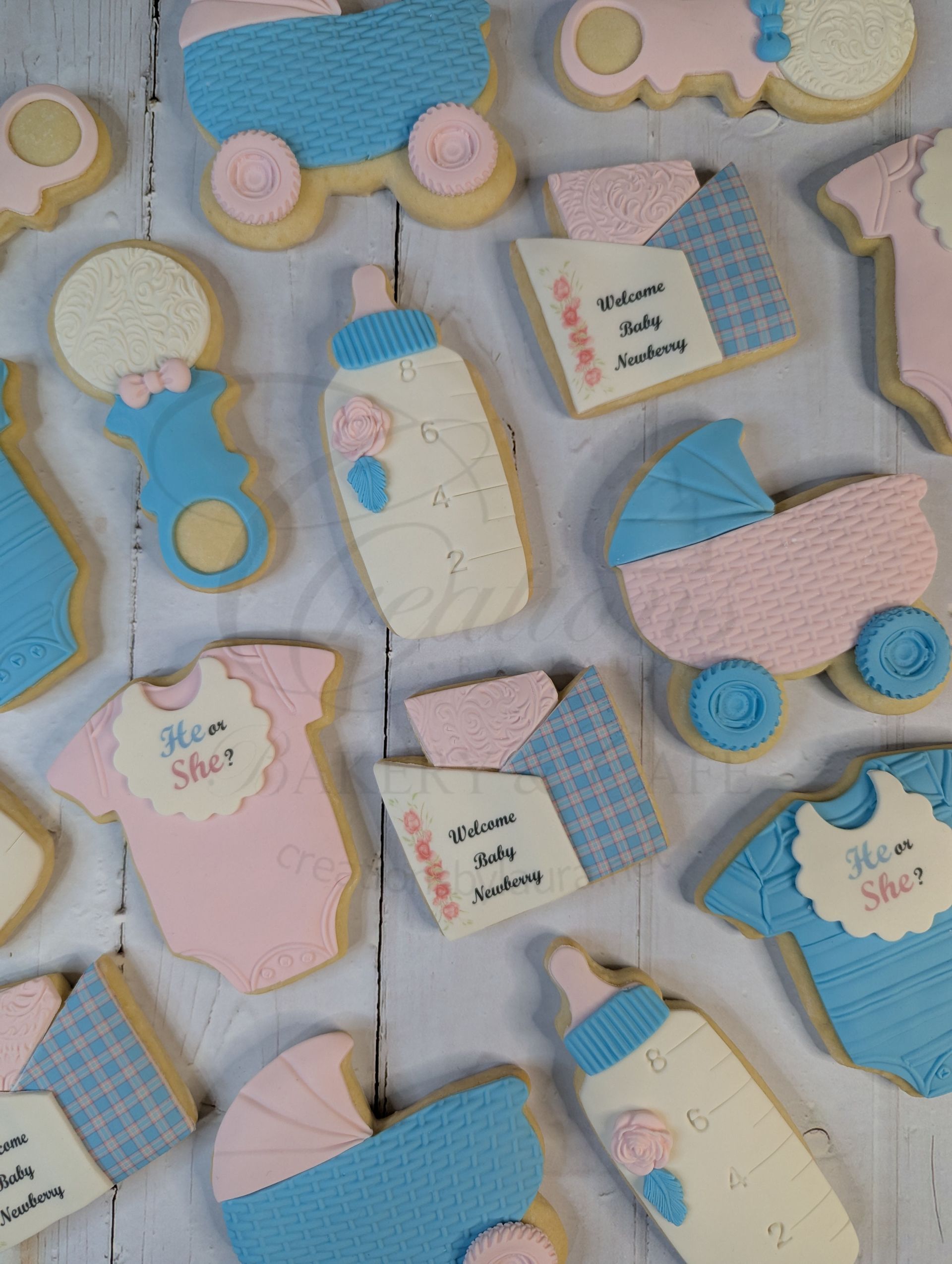 Pastel baby-themed cookies with blue, pink, and white icing on a light background.