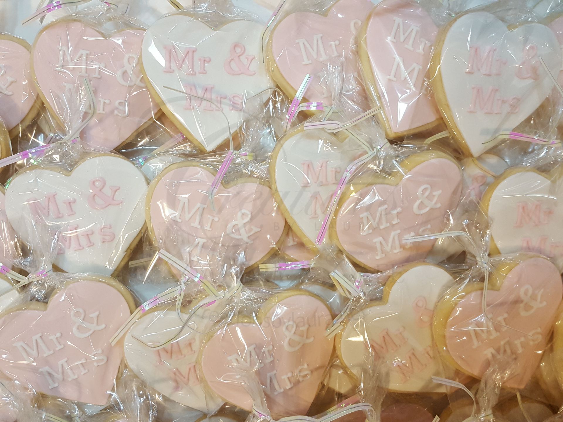 Pastel heart-shaped cookies wrapped in clear plastic, arranged closely together