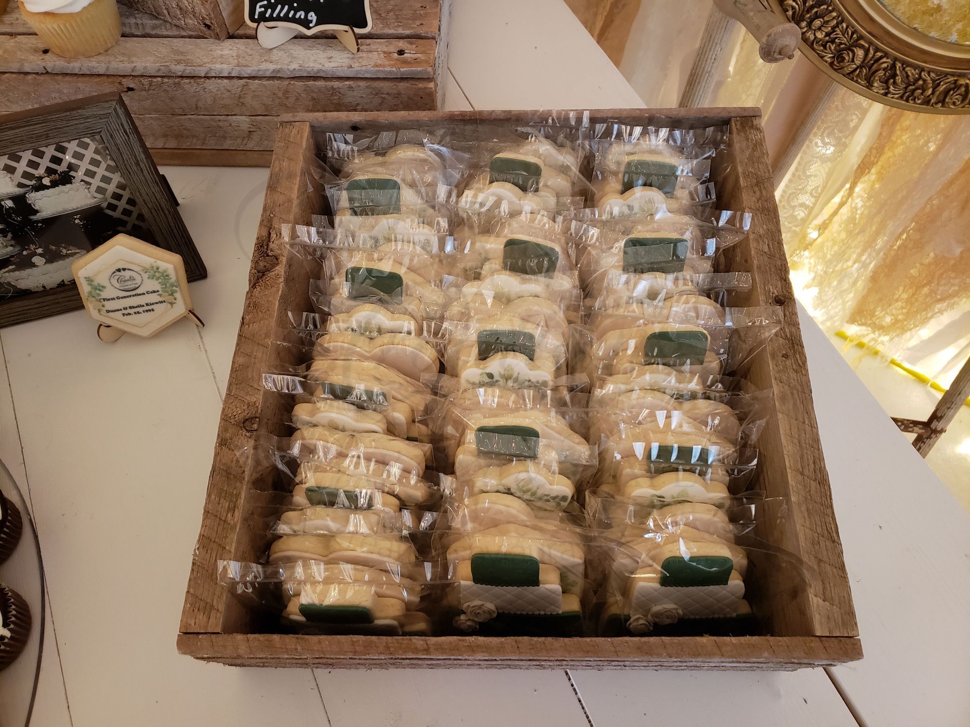 Tray of individually wrapped pastries in a wooden box on a table, beside a small decorative jar.