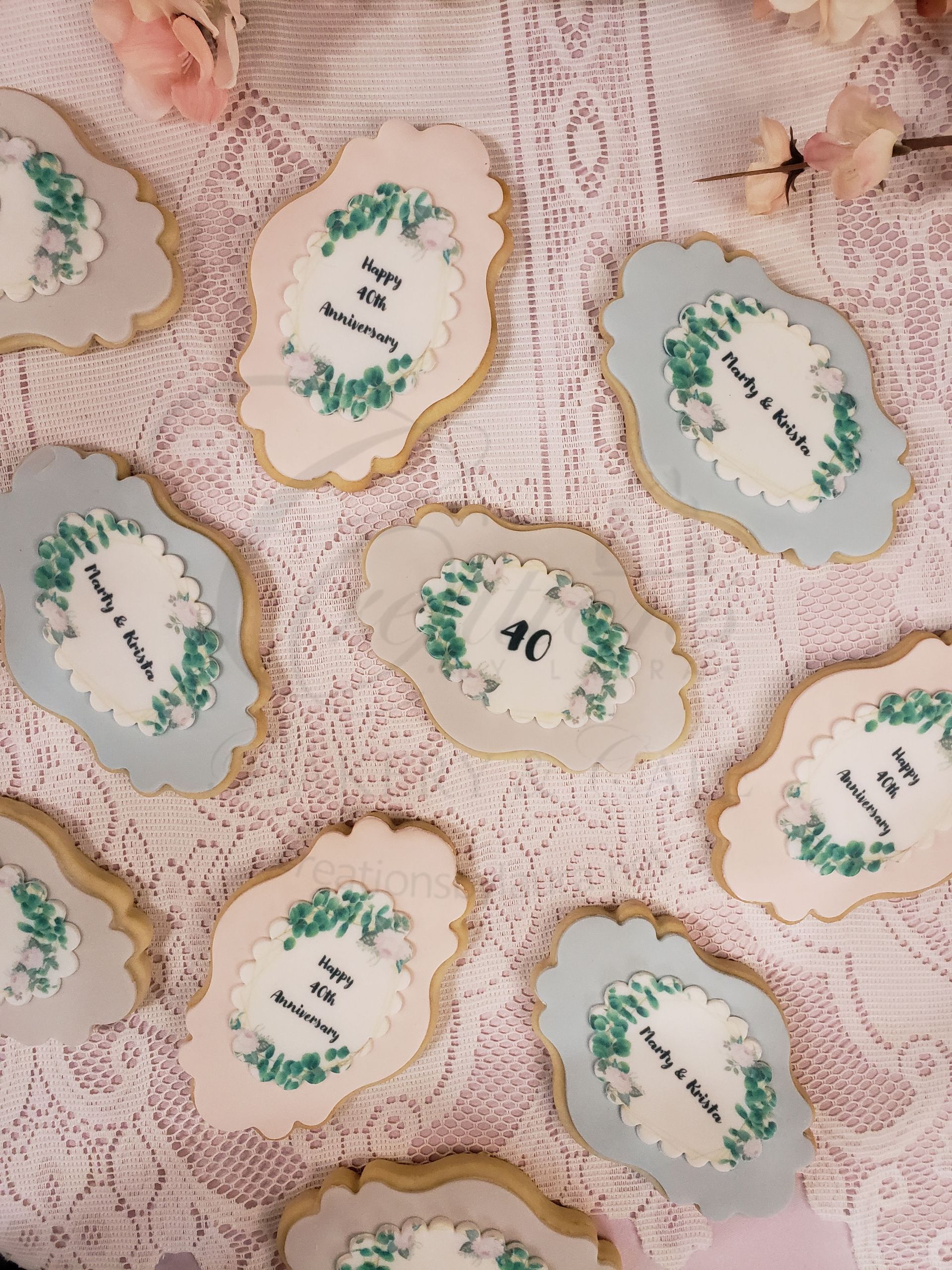 Pastel cookies with scalloped edges and green writing on a lace-covered surface