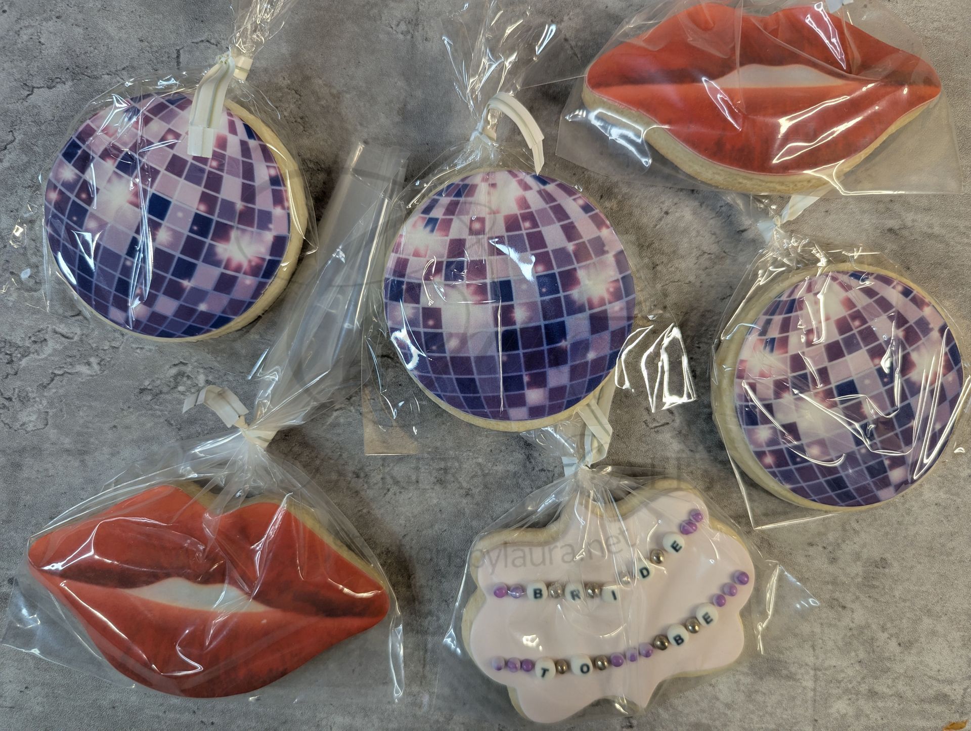 Assorted shiny lip-shaped and circular mosaic-patterned decorations in purple, red, and white on gray background