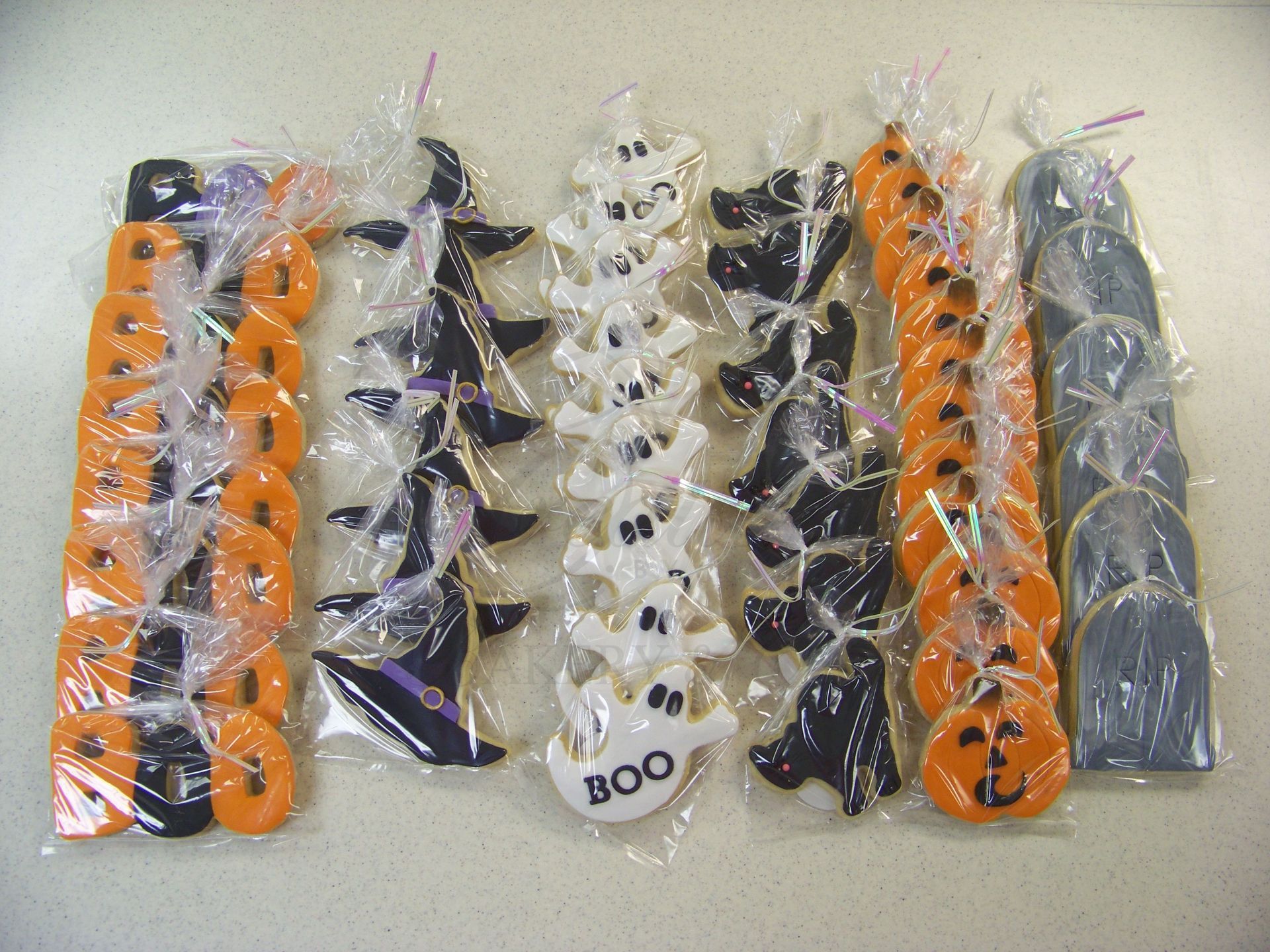 Assorted orange, black, and clear plastic cable clips and fasteners arranged in rows on a white background