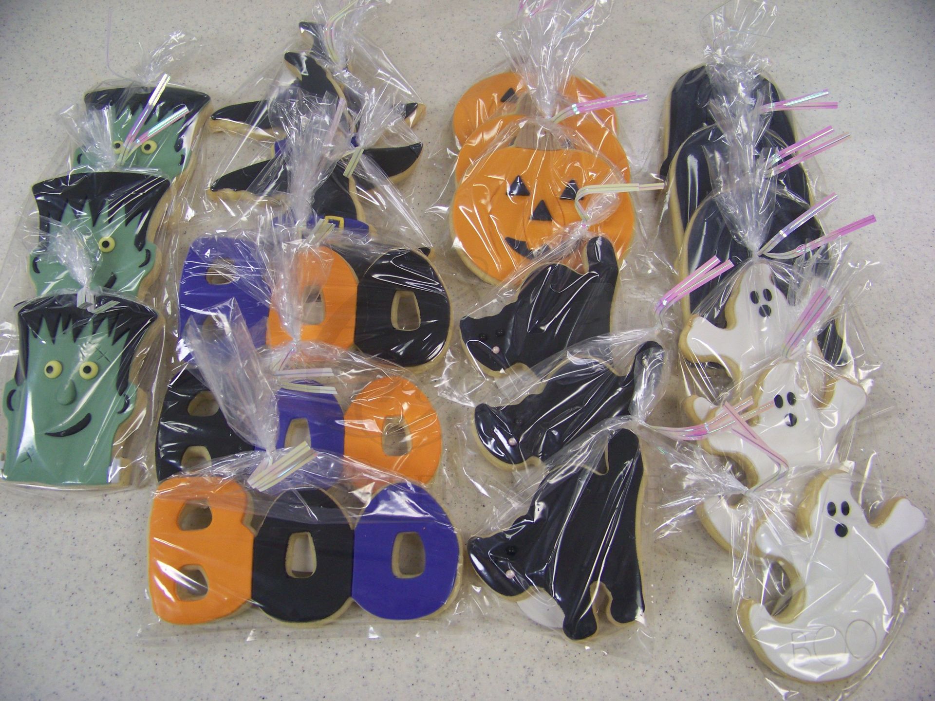 Assorted colorful ghost-shaped Halloween decorations in plastic packaging on a table