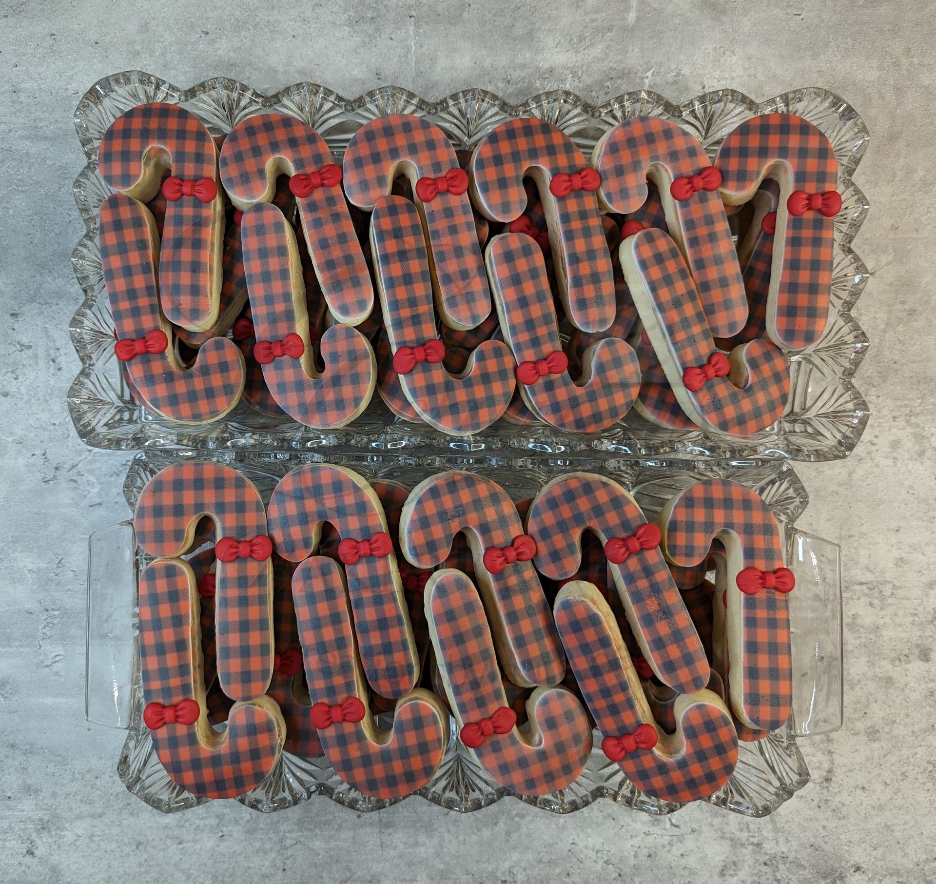Two rows of plaid fabric looped items on a gray surface, arranged in a decorative pattern.