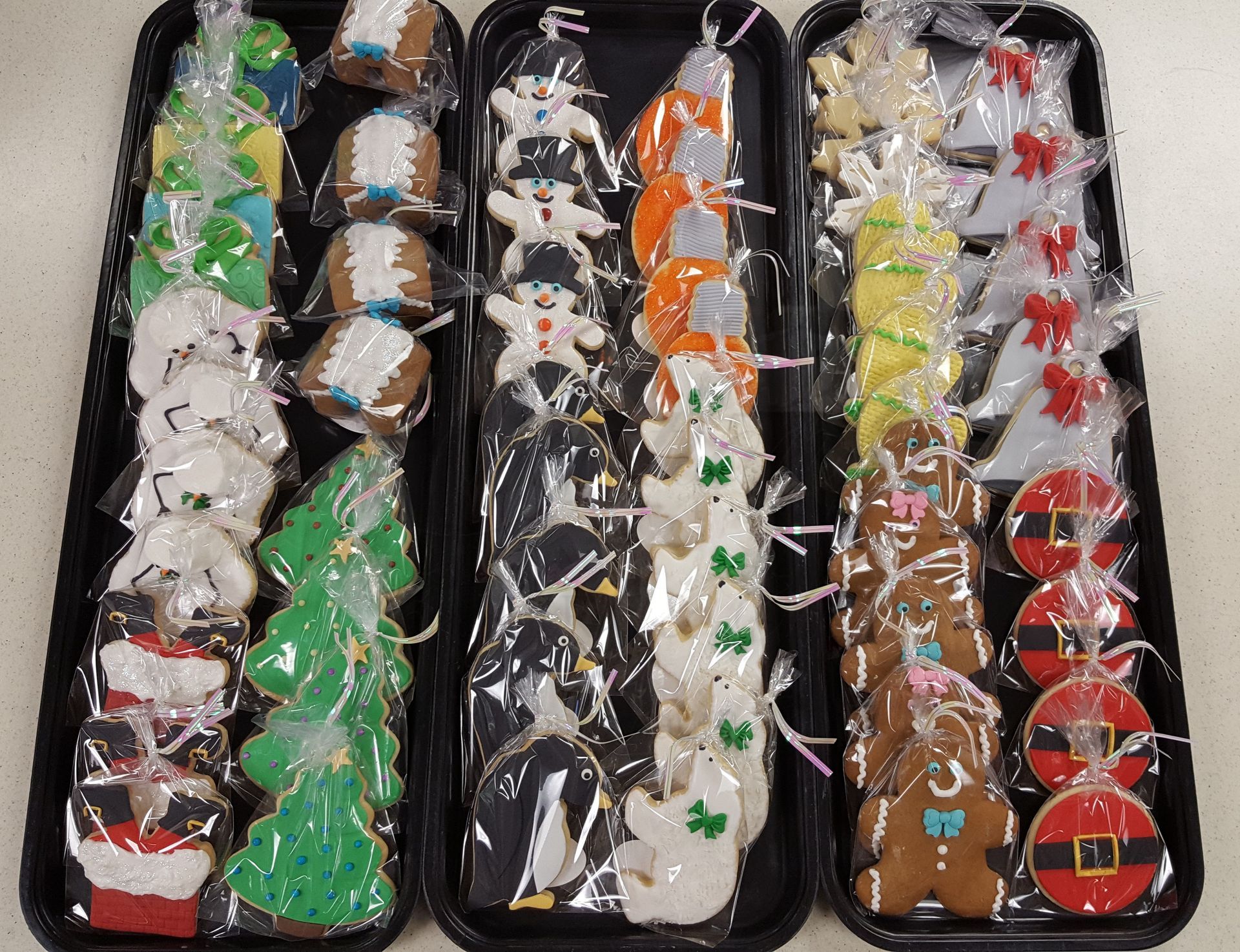 Assorted decorated Christmas cookies arranged in four trays with colorful icing and sprinkles.