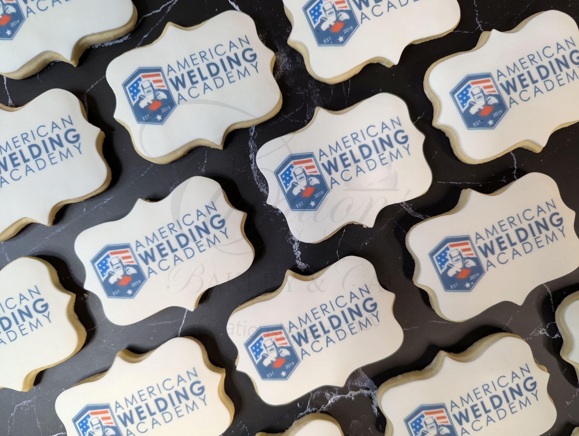 Rows of American Welding Academy logo badges with white and black edges on a dark background.