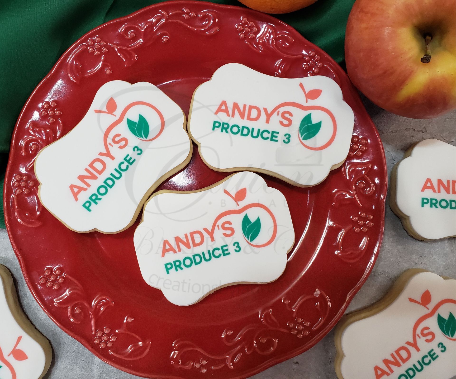 Red plate with several white apple-shaped Andy's Produce stickers on a produce display.